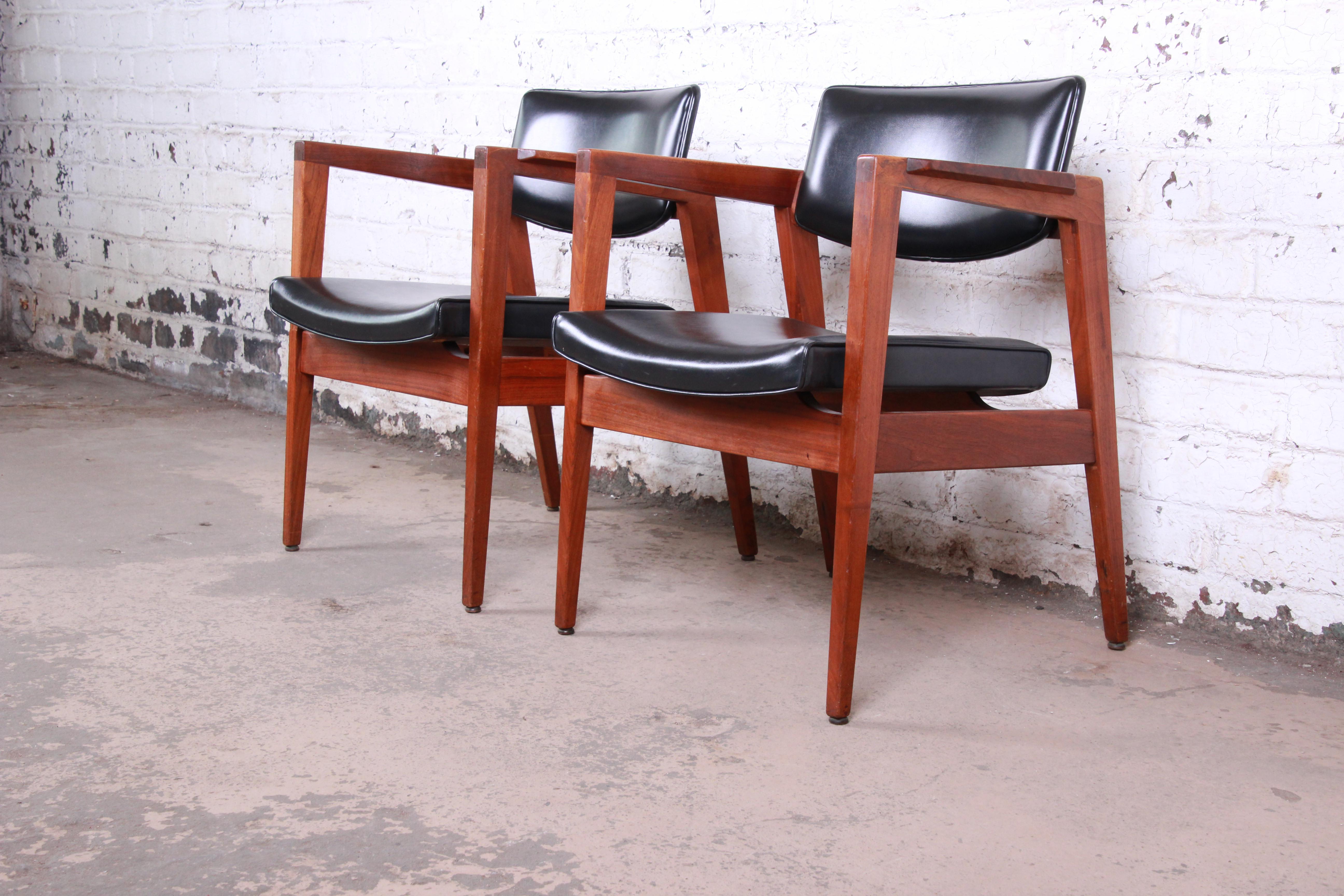 A gorgeous pair of Jens Risom style mid-century modern walnut lounge chairs by the Gunlocke Chair Co. of New York, circa 1960. The chairs feature sleek sculpted solid walnut frames, with a floating seat and back in original black vinyl. The original