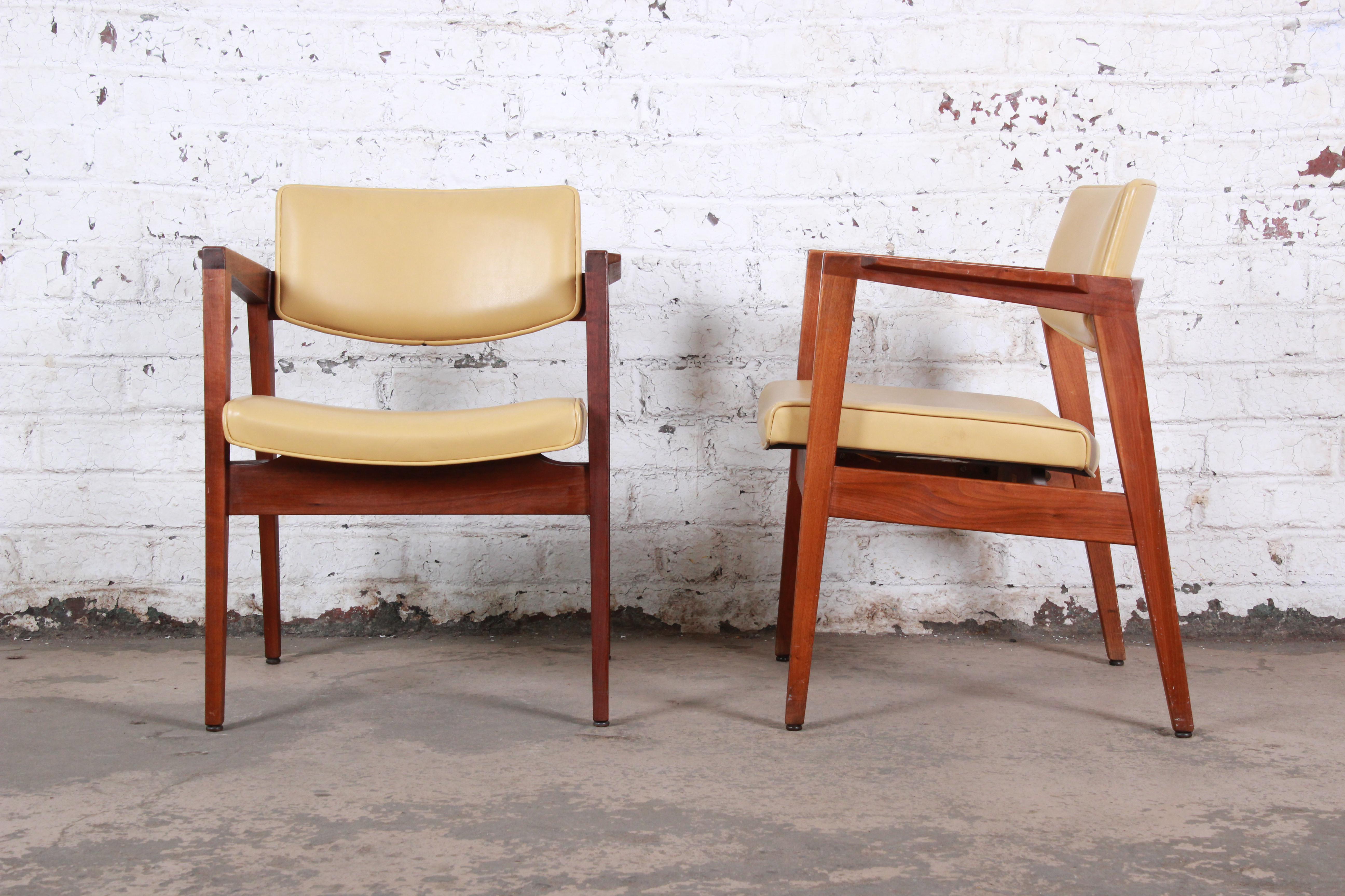A gorgeous pair of Jens Risom style Mid-Century Modern walnut lounge chairs by the Gunlocke Chair Co. of New York, circa 1960. The chairs feature sleek sculpted solid walnut frames, with a floating seat and back in original yellow vinyl. The