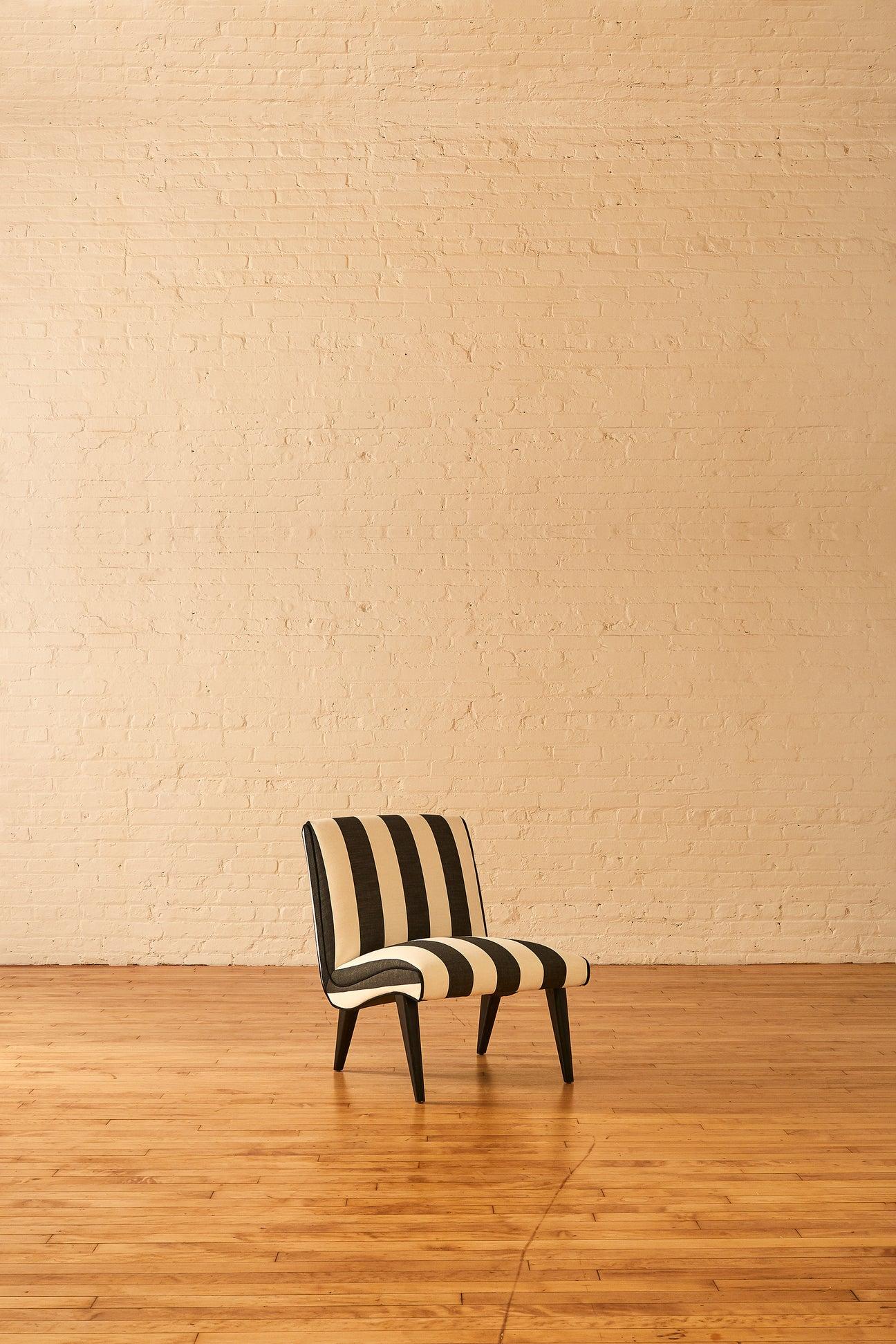 A Jens Risom style lounge chair with a scoop design and shape. The chair has dark splayed wood legs and was reupholstered with a cotton twill black and white awning stripe complete with black piping.