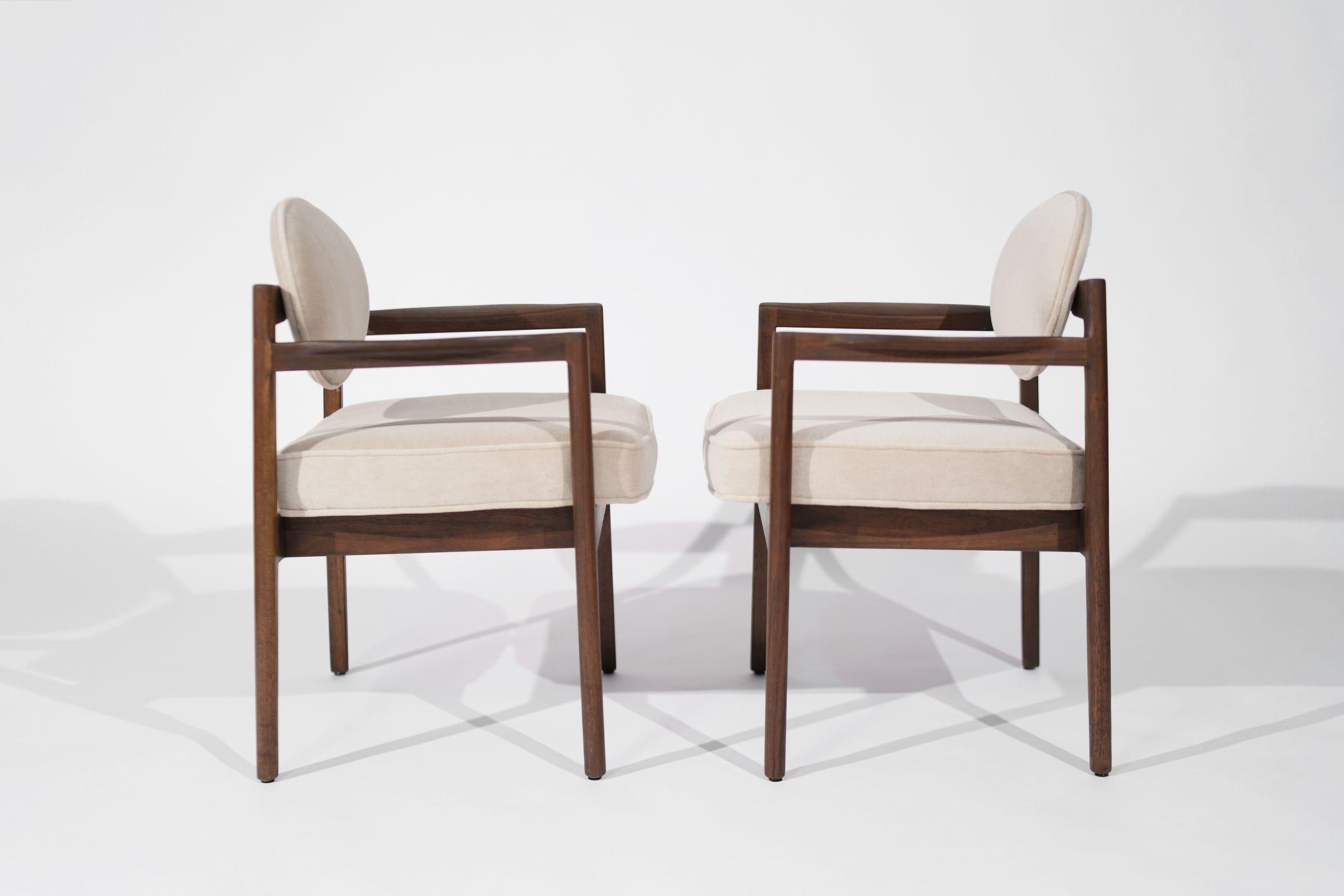 An exquisite pair of mid-century modern armchairs designed by Jens Risom, crafted circa 1960-1969. Meticulously restored, the walnut framework shines with renewed beauty, complemented by a luxurious reupholstery in natural mohair. A perfect blend of