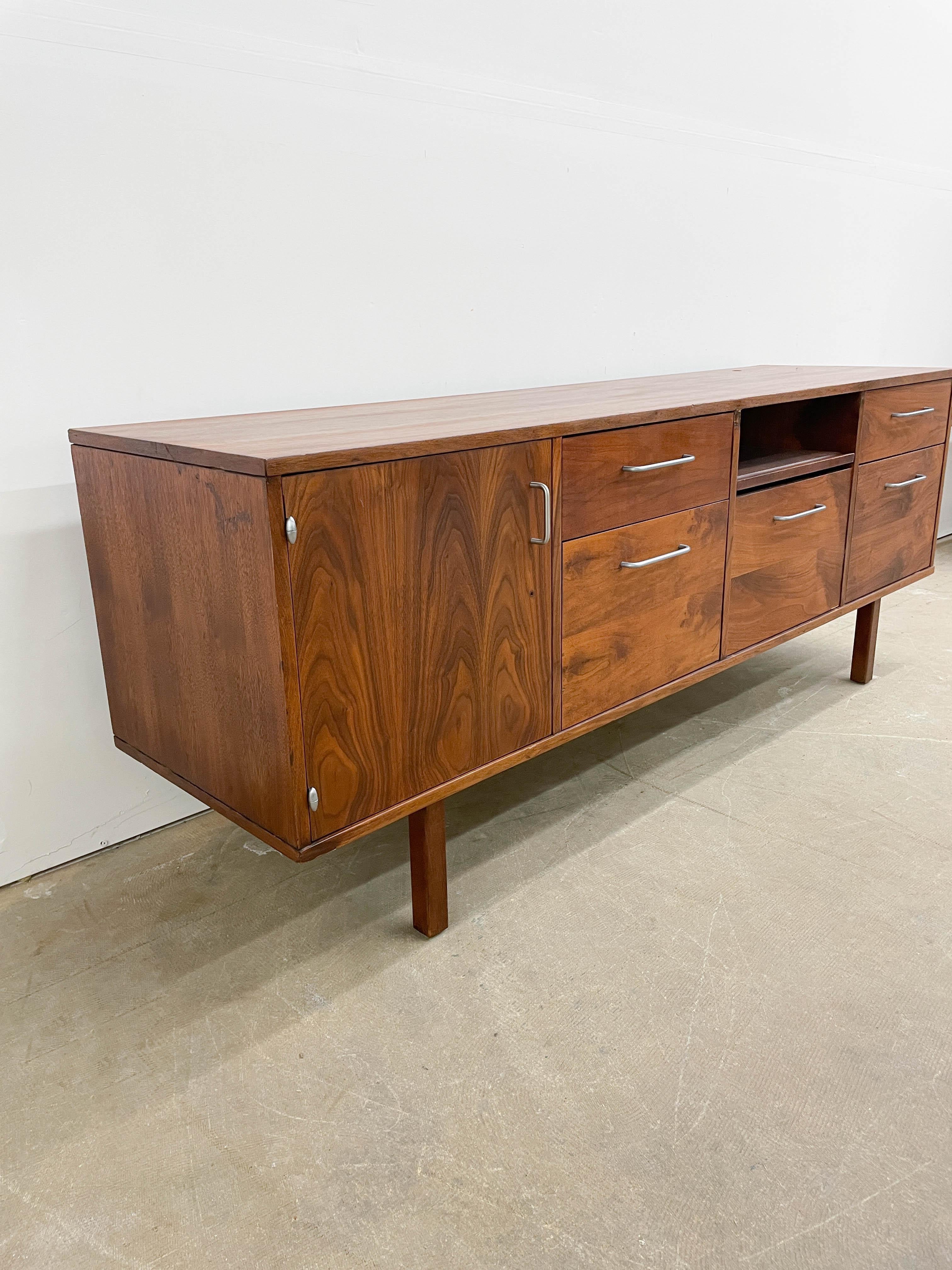 Functional and understated walnut credenza designed by Jens Risom for his own company, Jens Risom Design in the 1950s. This pieces features five drawers, two of which are hanging file drawers, a slide out typewriter tray and a larger storage