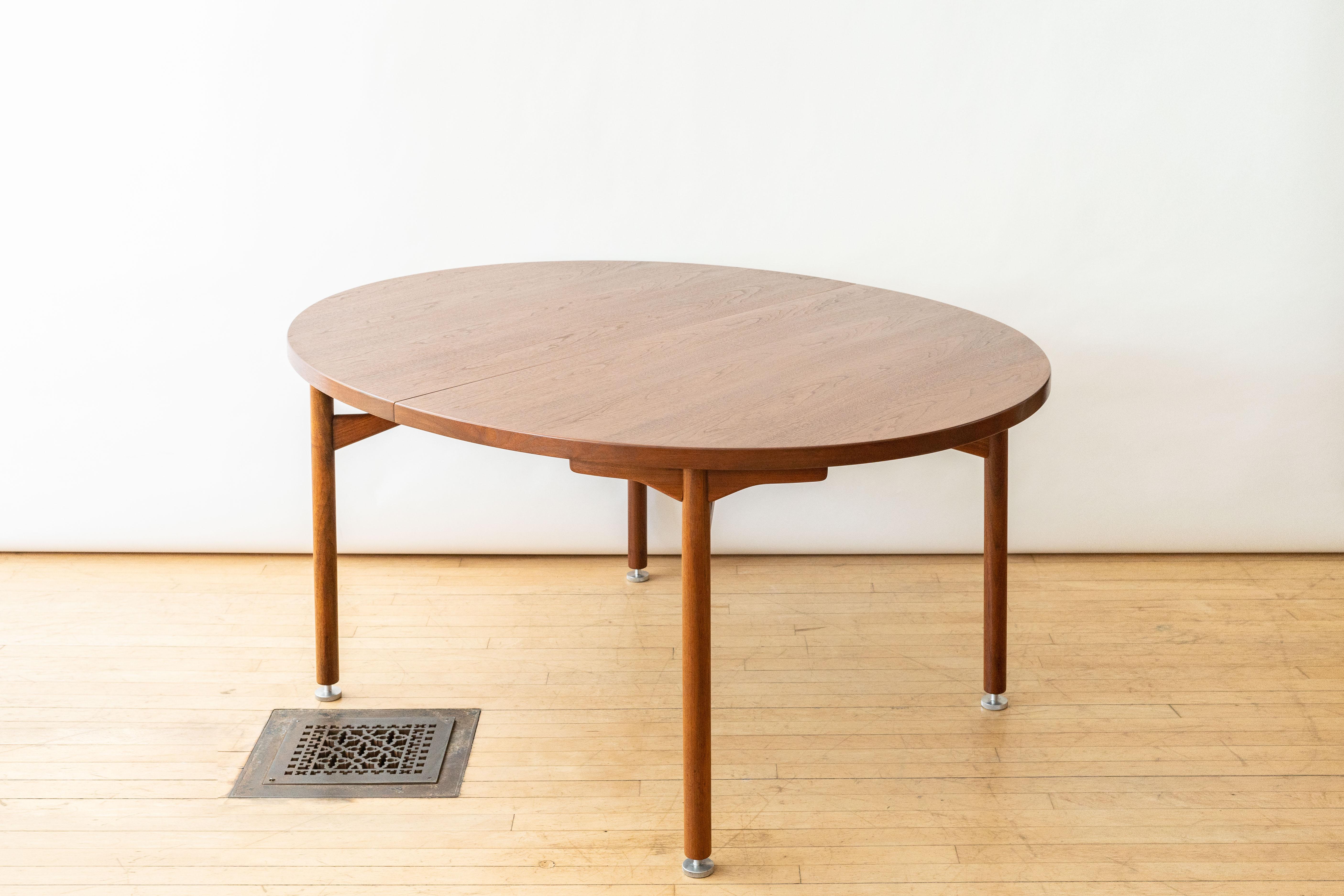 USA, ca. 1960s. An attractive Model T-181 dining table by Jens Risom for his company Jens Risom Design. Features sturdy walnut construction with beautifully grained oval top supported by solid cylindrical legs. Sculptural brackets ensure stability