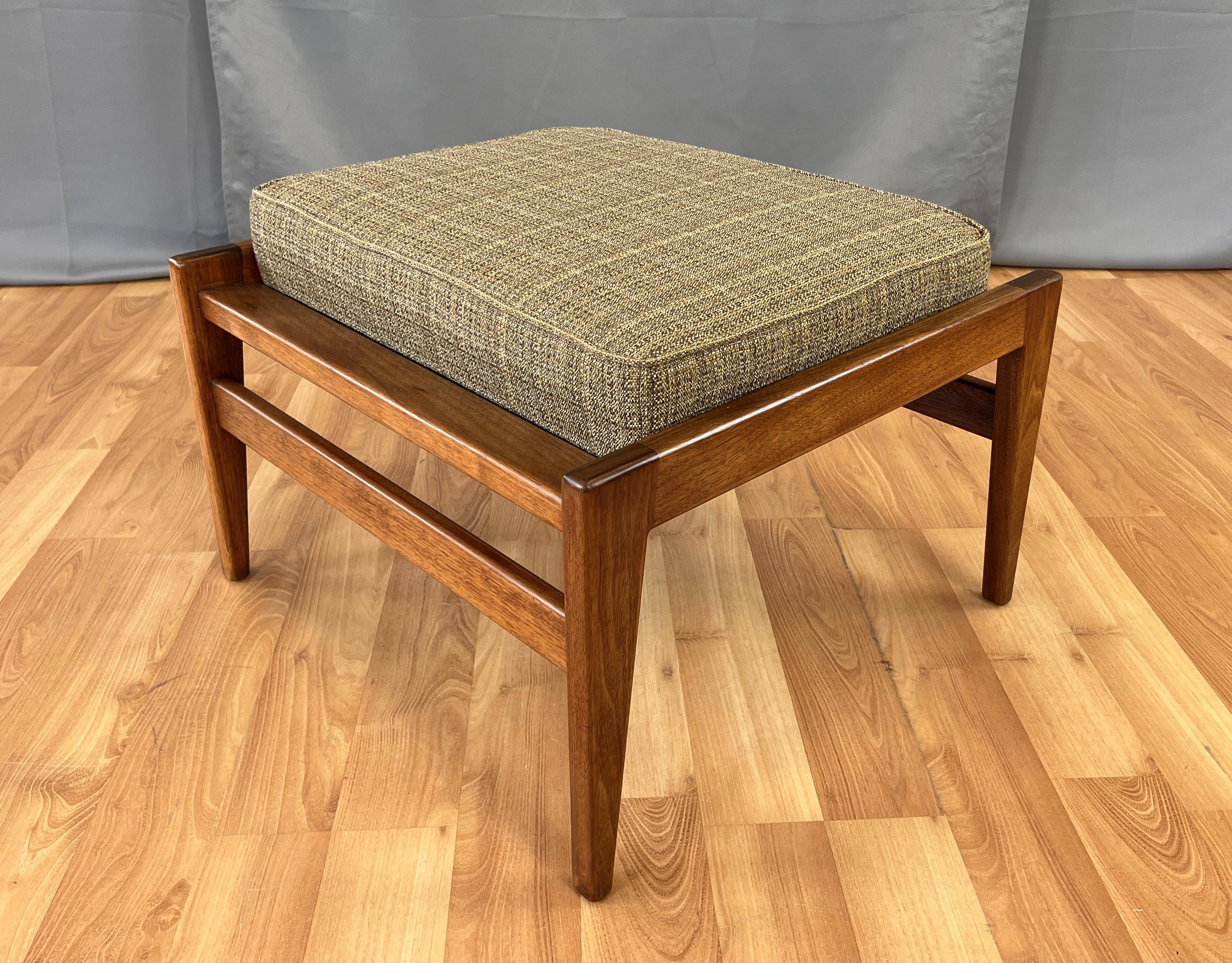 Offered here is a Jens Risom designed Walnut ottoman (signed under upholstery), angular framework and in the center sits the cushion that's built into the frame.
Ottoman has an edge on two side, which is a nice design touch, fabric feels to be a