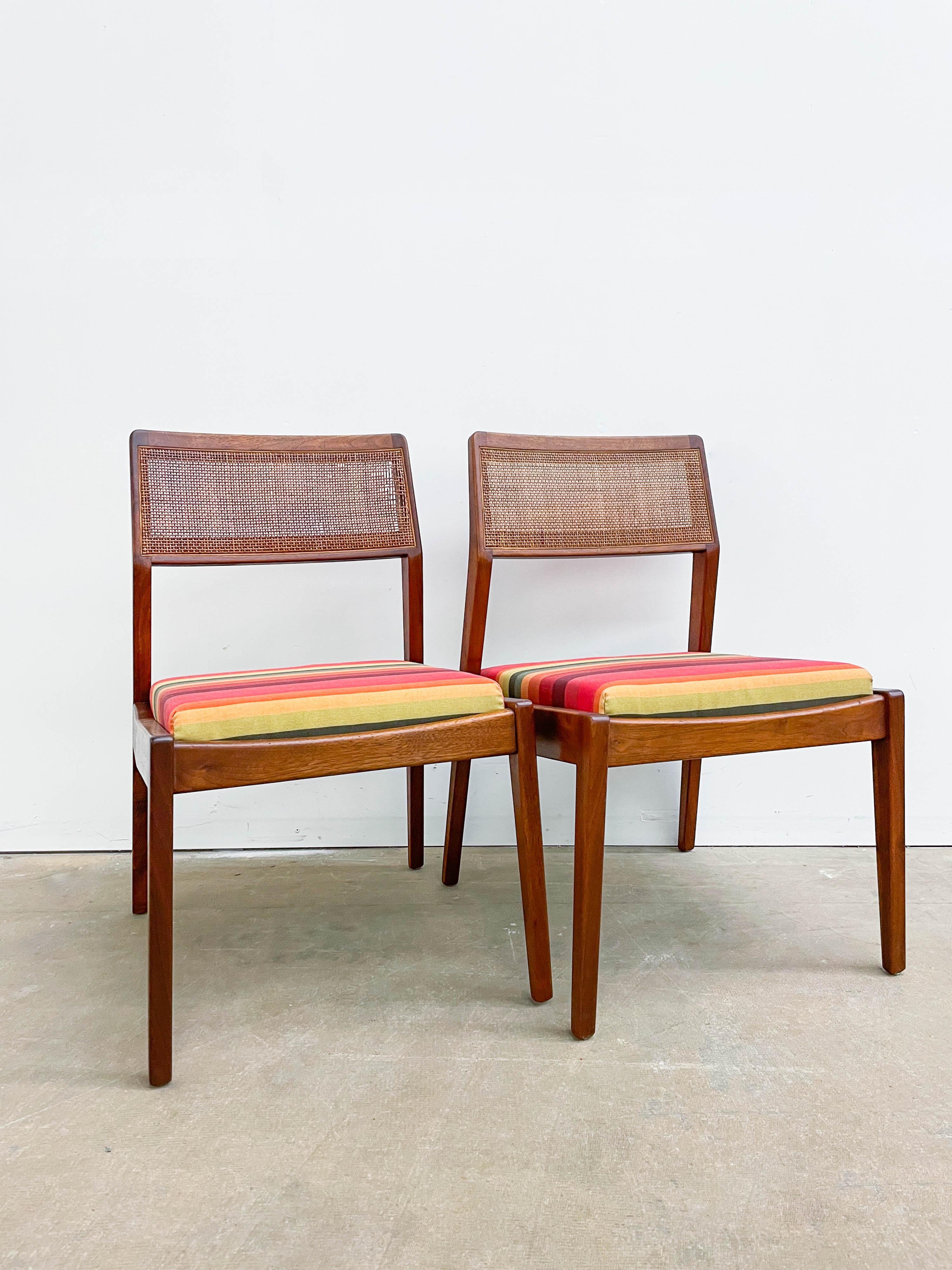 A pair of solid walnut side chairs designed by Jens Risom in the 1950s. The original cane backs add a nice texture and lightness to the design. Newly upholstered in a rainbow fabric with new foam for a durable and comfortable seat. Both chairs are
