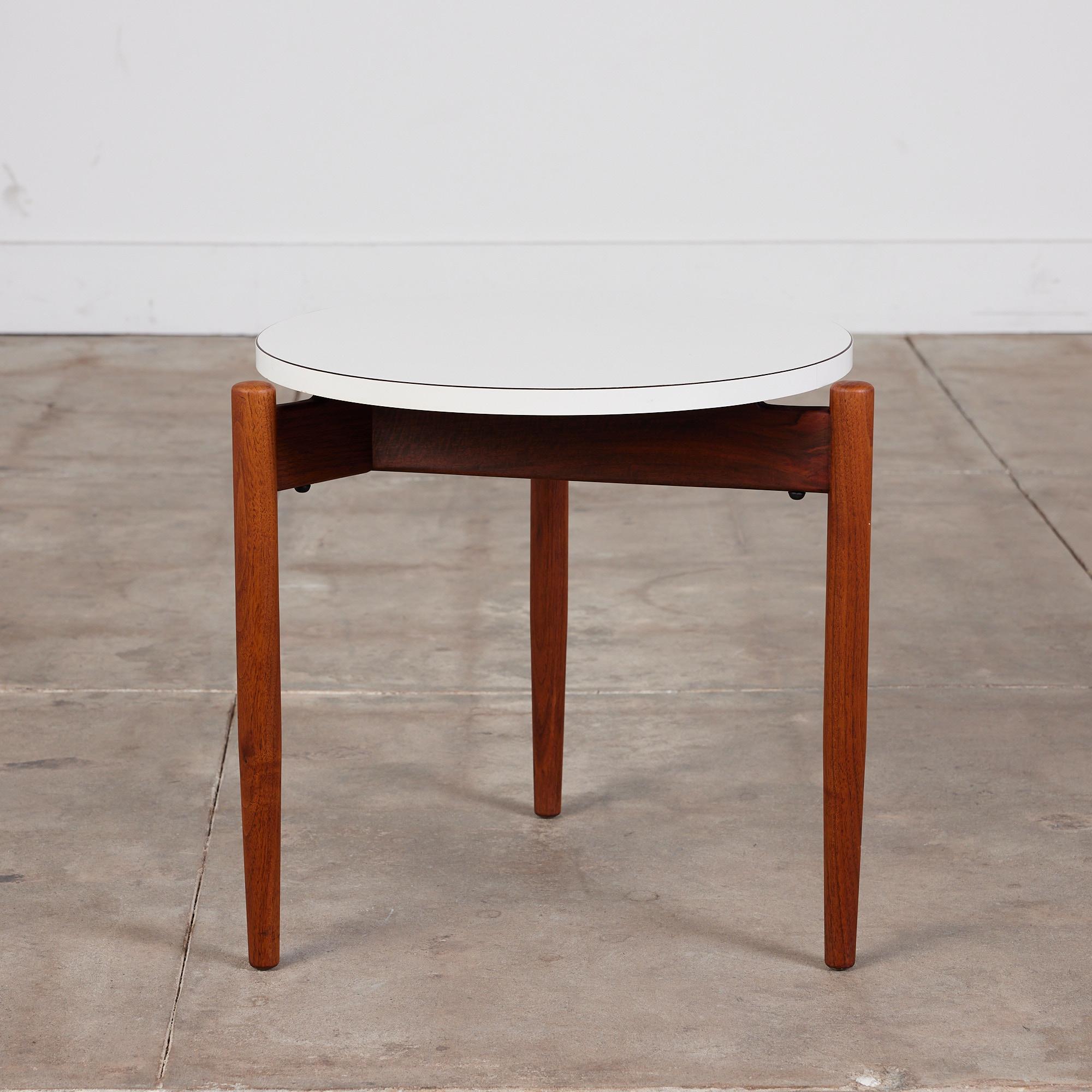 Round walnut side table by Jens Risom for Risom Design, USA, c.1960s. The table features a round white laminate table top with three tapered legs that sit proud of the edge of the laminate table top.

Dimensions: 19.5