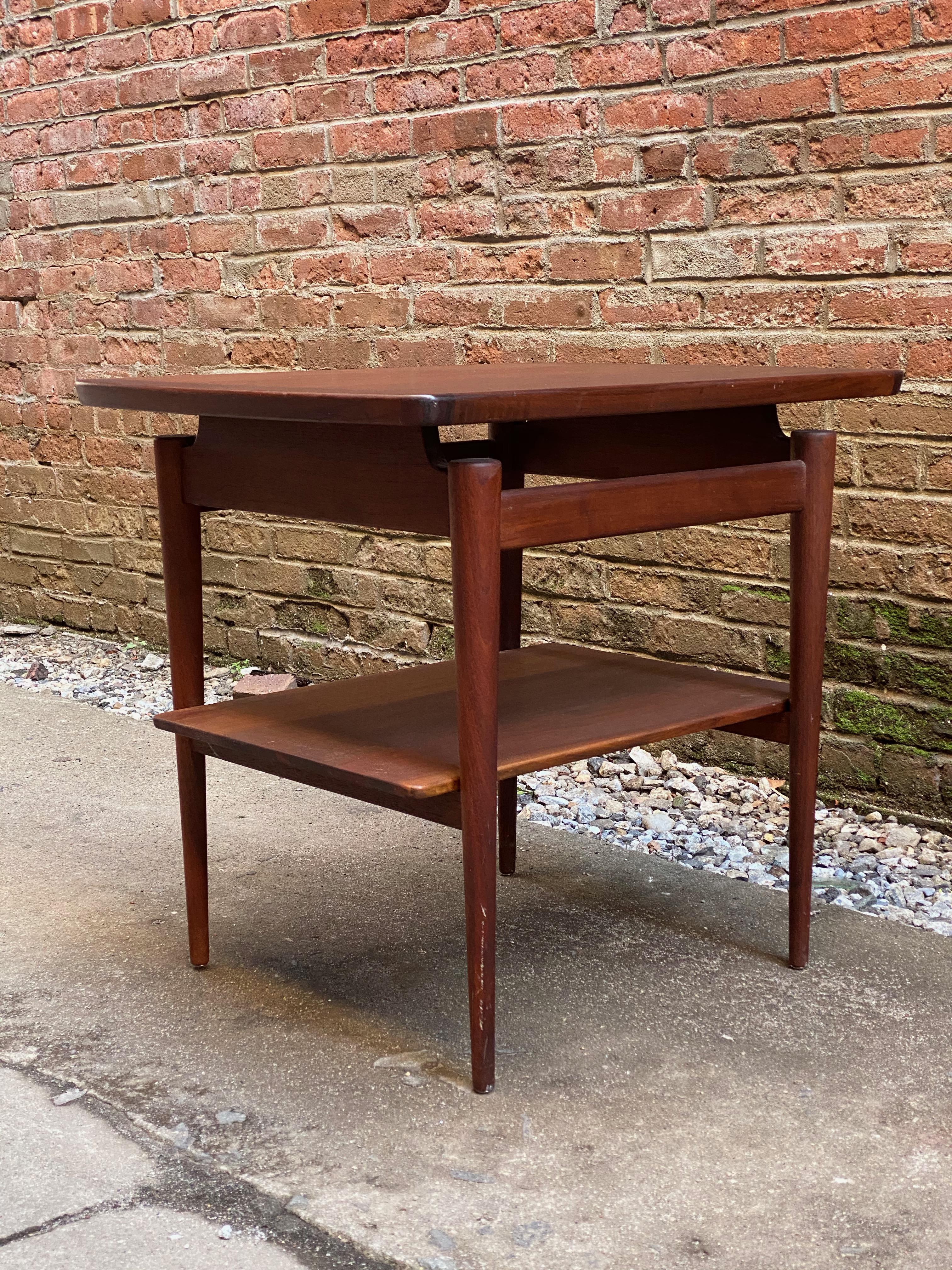 Jens Risom design T-490 floating top walnut end table. Solid walnut round tapered legs, floating top with lower shelf. 

Measures: 27