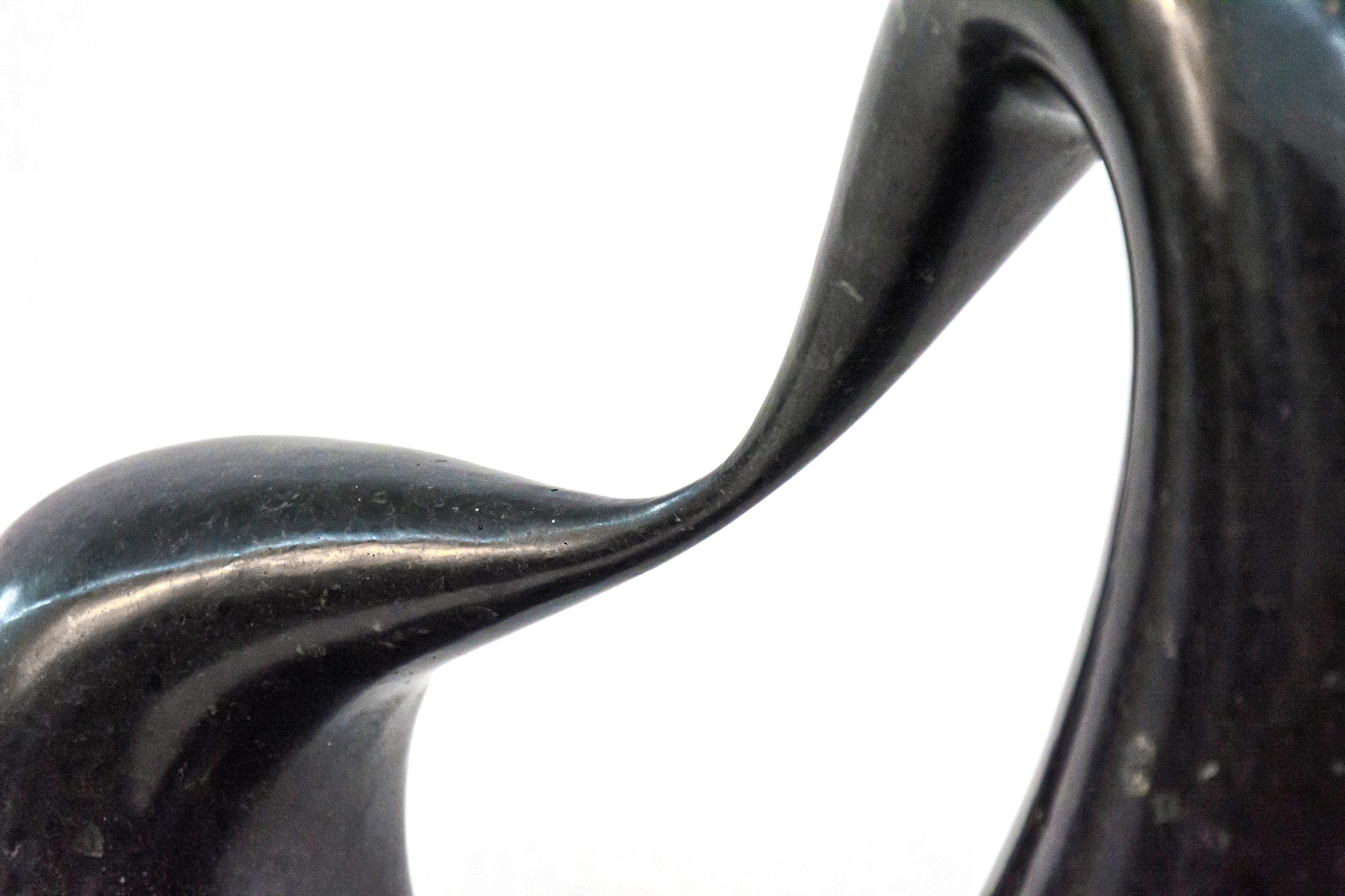 Glatter, schwarzer Marmor mit kupferfarbenen und weißen Sprenkeln wird bei dieser Tischskulptur zu einer dicken Schlaufe geformt, die an einer Seite dünn ausgezogen ist. Die auf einem flachen Metallsockel stehende, abgeflachte Schlaufe weist einen