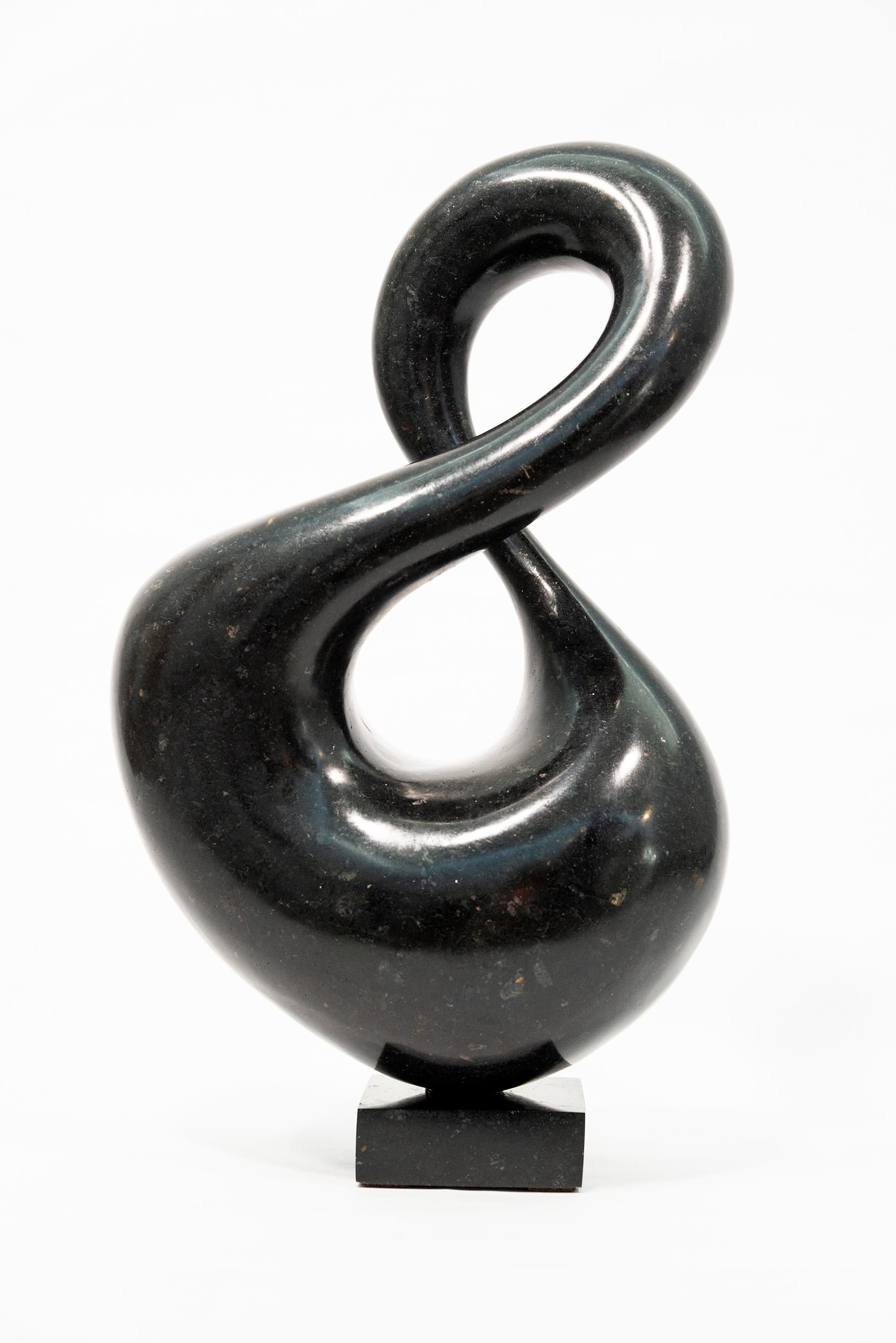 With its fluid and elegant lines, this abstract stone sculpture by Jeremy Guy appears to resemble a figure eight. Guy is known for his powerful contemporary form that often emulates shapes found in nature. Created from engineered black granite, this
