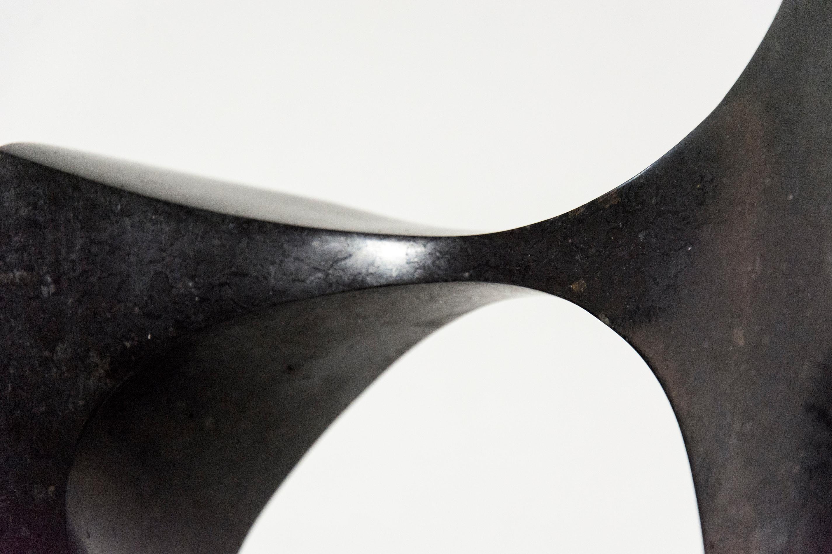 Smooth surfaced, engineered black granite is sculpted into an elegant figure eight by Jeremy Guy. The hour glass shaped work is aptly titled Halcyon which points to a period that is calm and idyllic. This sculpture work sits vertically without a
