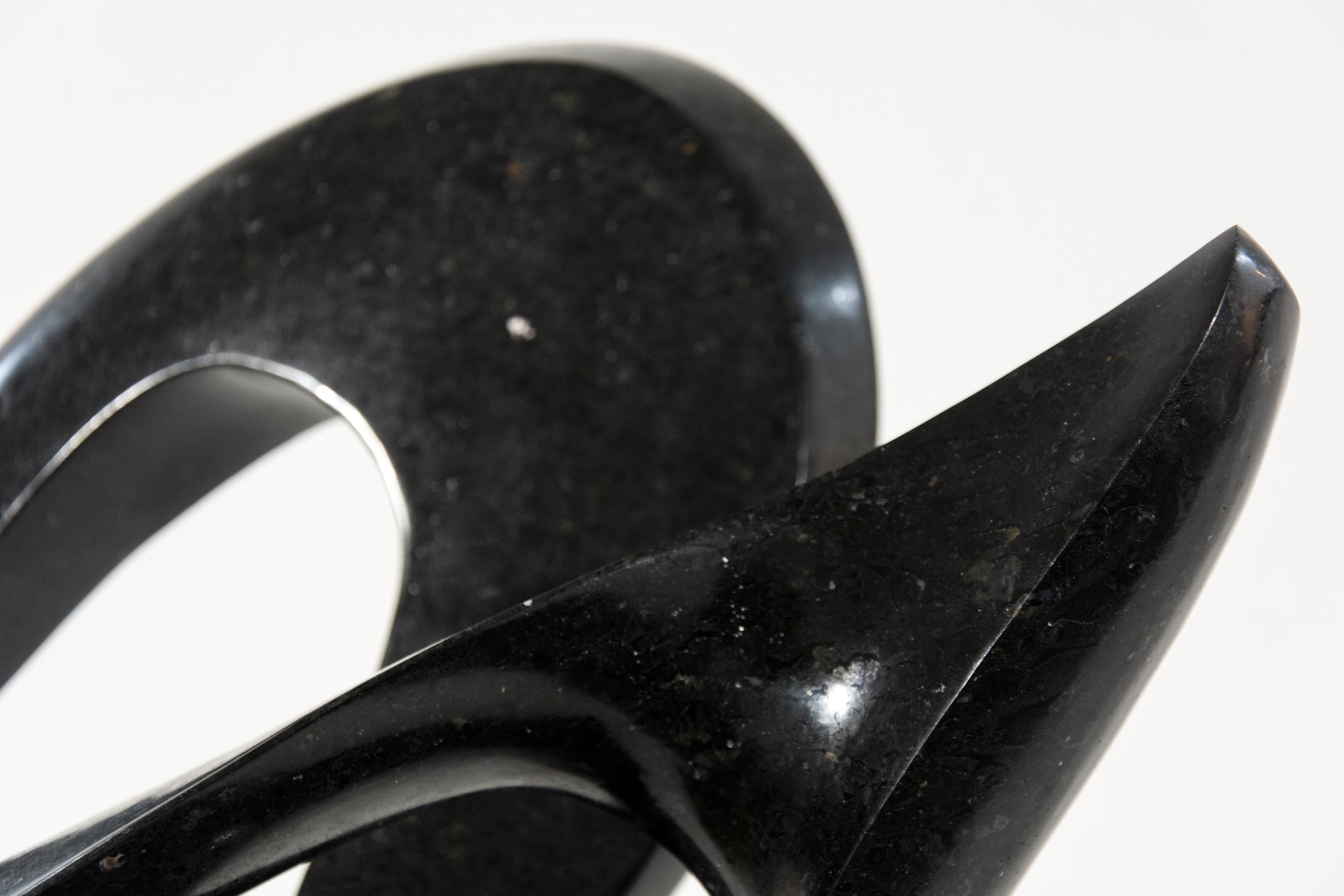 Smooth surfaced, engineered black granite is sculpted into an elegant, spinning form by Jeremy Guy. This lively shape that appears to spin dynamically on its narrow base, like a pirouette on one foot, is mounted on a granite base. It is number 20 in