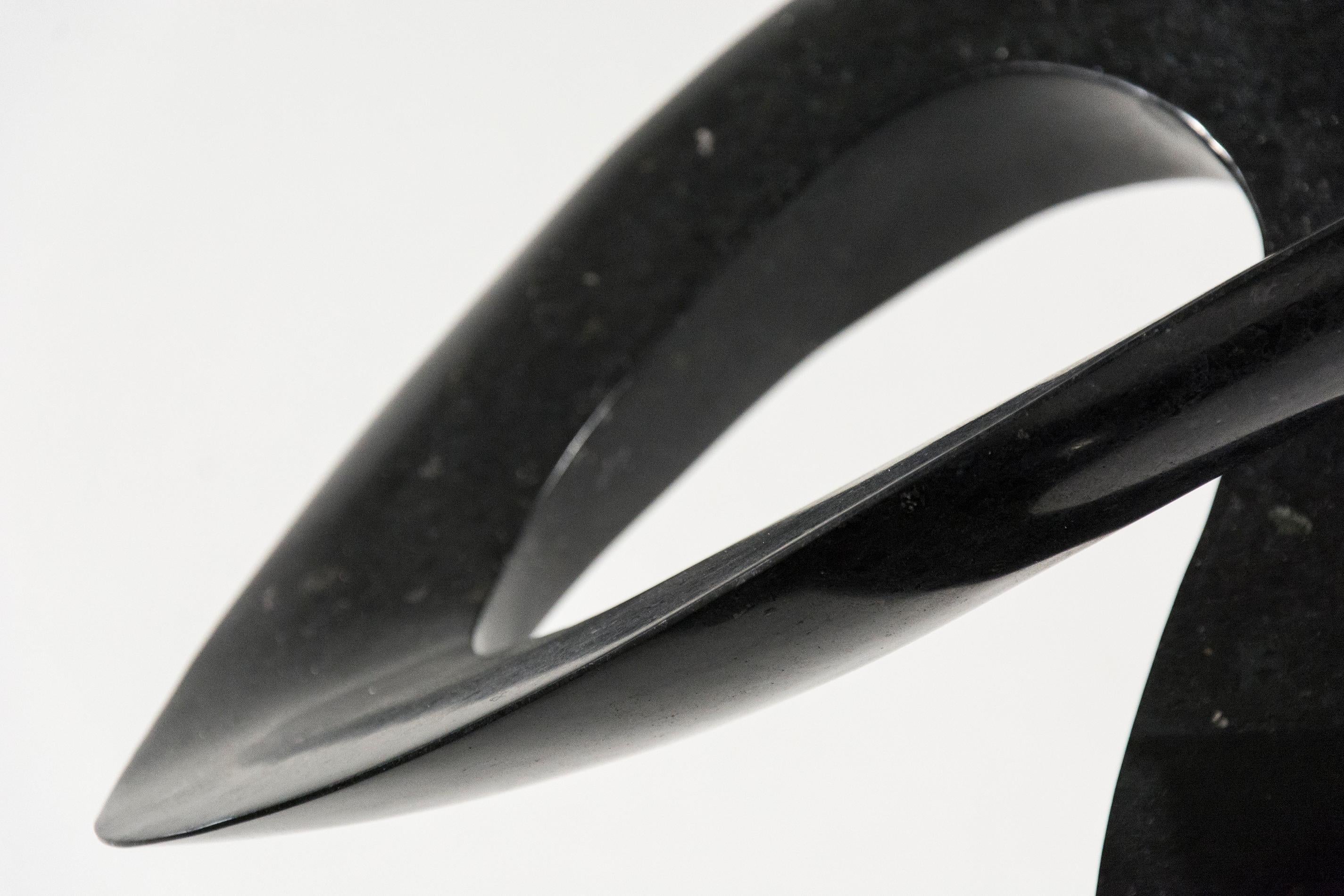 Smooth surfaced, engineered black granite is sculpted into an elegant, spinning form by Jeremy Guy. This lively shape that appears to spin dynamically on its narrow base, like a pirouette on one foot, is mounted on a square granite base. 

Jeremy