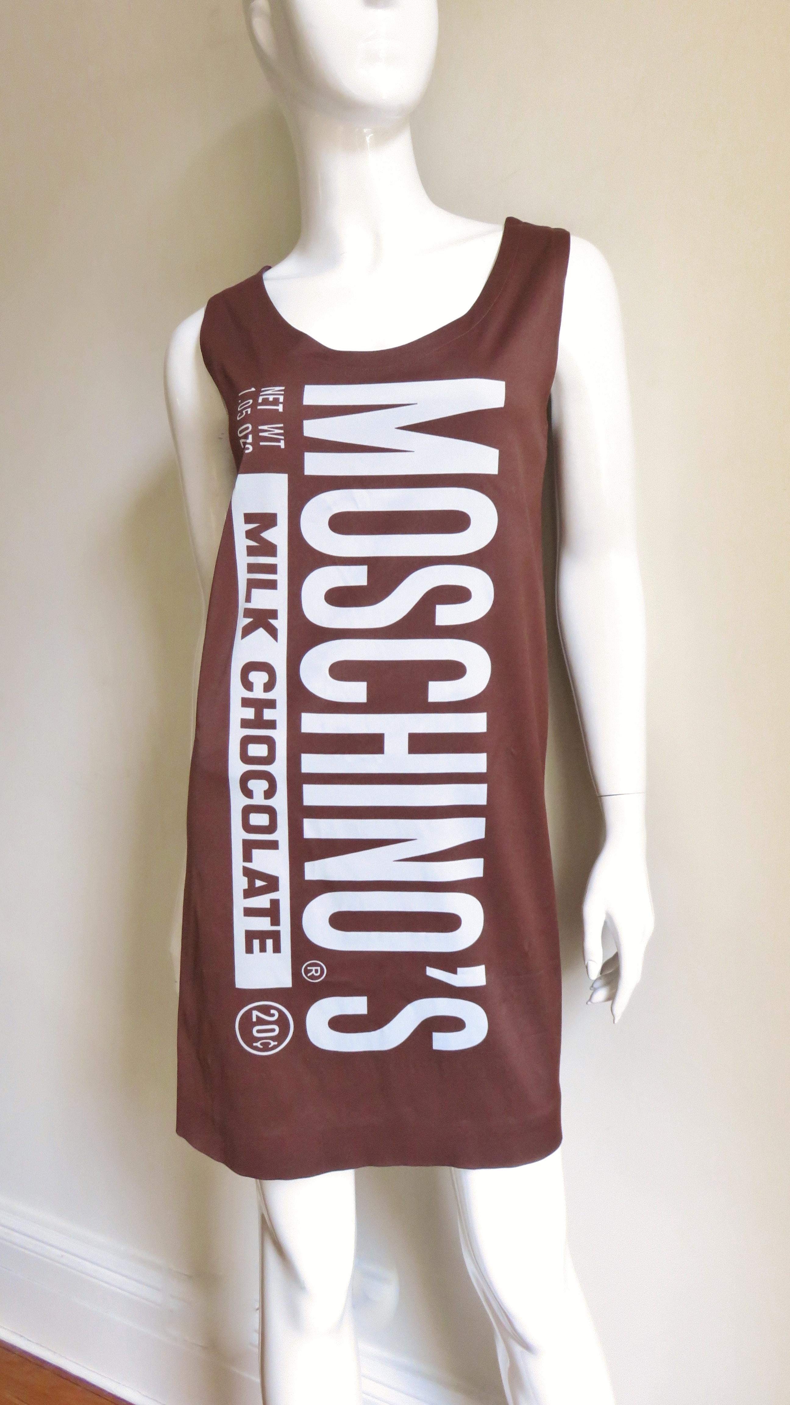 From the whimsical F/W 2014-2015 Jeremy Scott collection for Moschino.
It is a shift dress in a chocolate brown jersey with white lettering mimicking the front of a chocolate bar wrapper. On the back are the nutritional components. It is sleeveless