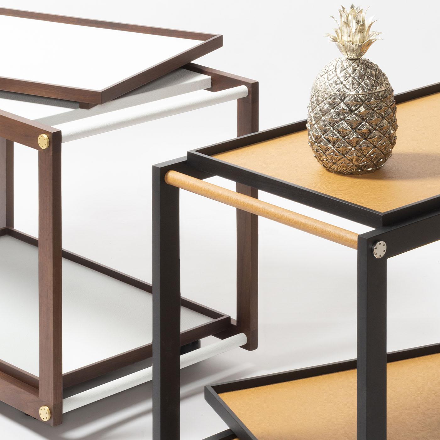 Wood structure is available in different finishes featuring fine leather and metal inserts. Provided with two removable trays and omnidirectional wheels. Different walnut wood finishes and metal are available upon request.