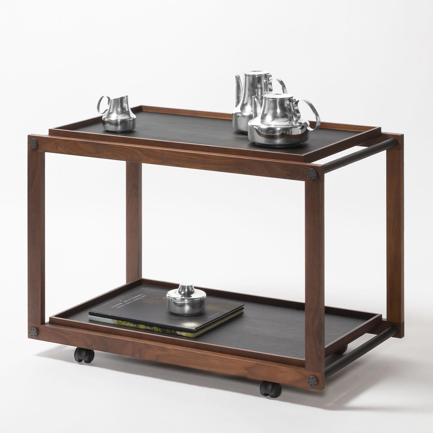 Wood structure is available in different finishes featuring fine leather and metal inserts. Provided with two removable trays and omnidirectional wheels. Different walnut wood and metal finishes are available upon request.