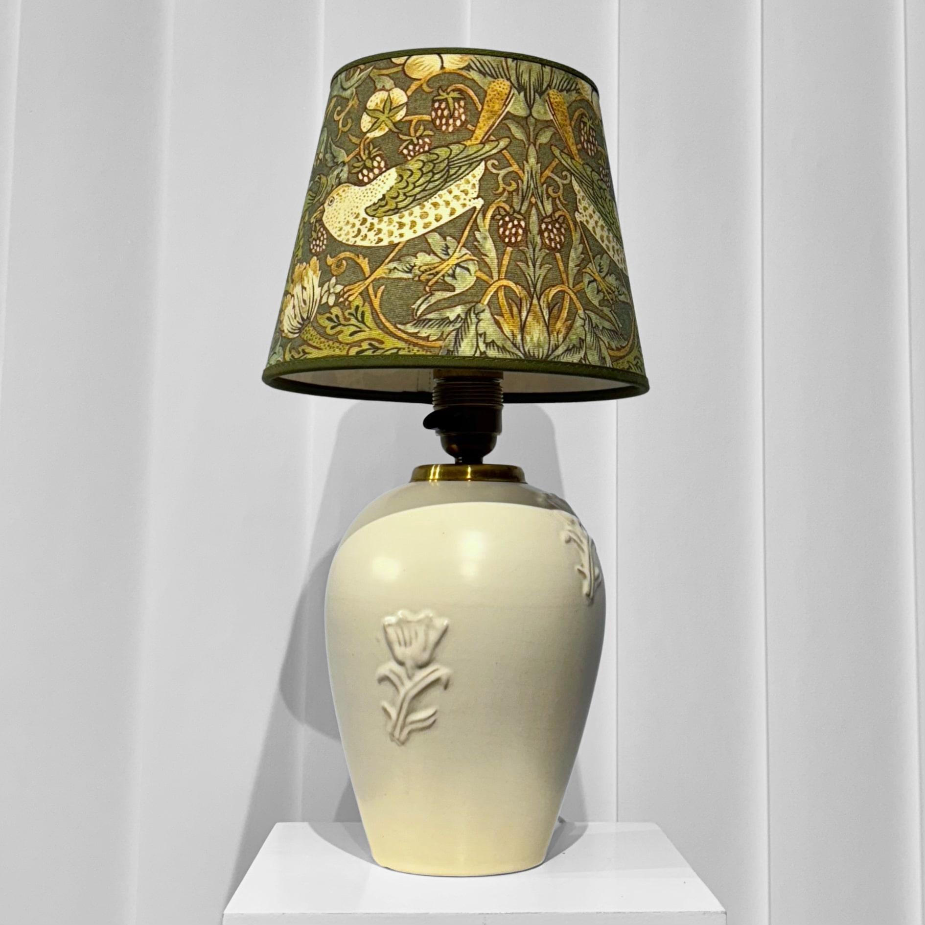 Eine exquisite Tischlampe, entworfen von Jerk Werkmäster um 1940 für das schwedische Keramikstudio Nittsjö. Der Sockel ist aus cremefarben glasiertem Steingut gefertigt und mit einem zarten Blumenrelief versehen. Die Leuchte ist mit einer