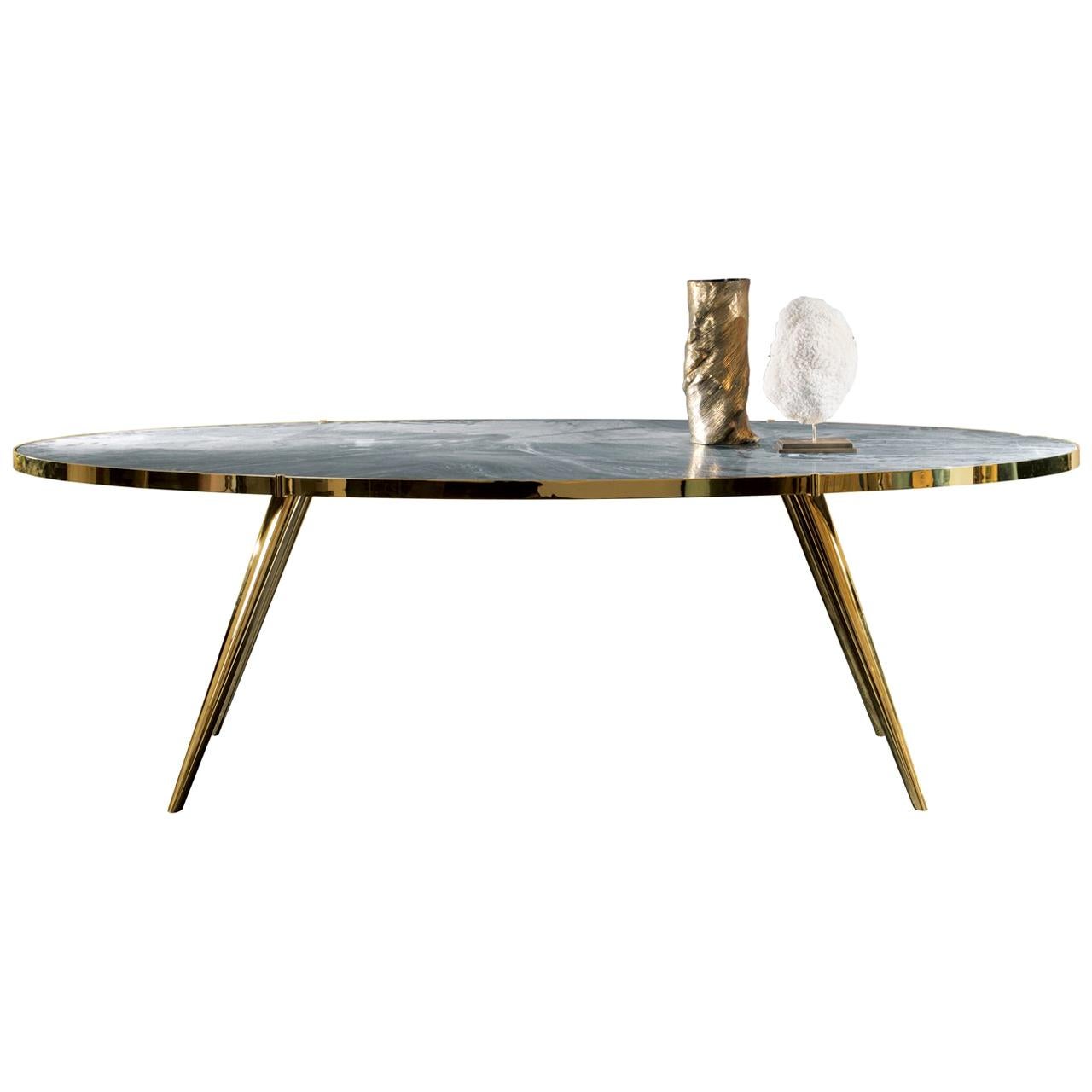 Part of the Jerome collection, this dining table boasts tapered and slanted legs that give it a midcentury allure, supporting an oval top. Sophisticated and timeless, this piece is made of metal with a glossy brass finish, included the mounting of