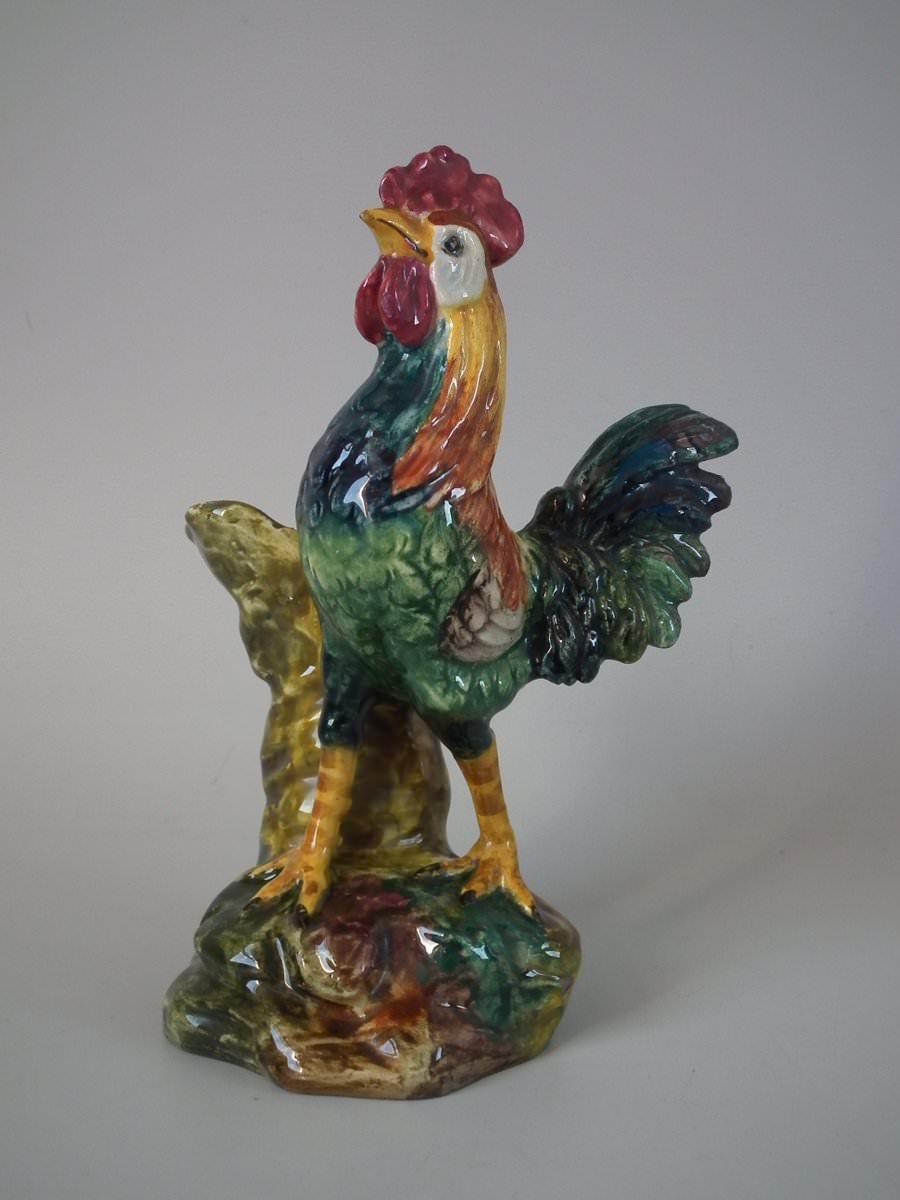 Jerome Massier Majolica vase which features a cockerel/rooster stood in front of a vase modelled in the form of a tree stump. Coloration: green, blue, ochre, are predominant. The piece bears maker's marks for the Jerome Massier pottery.