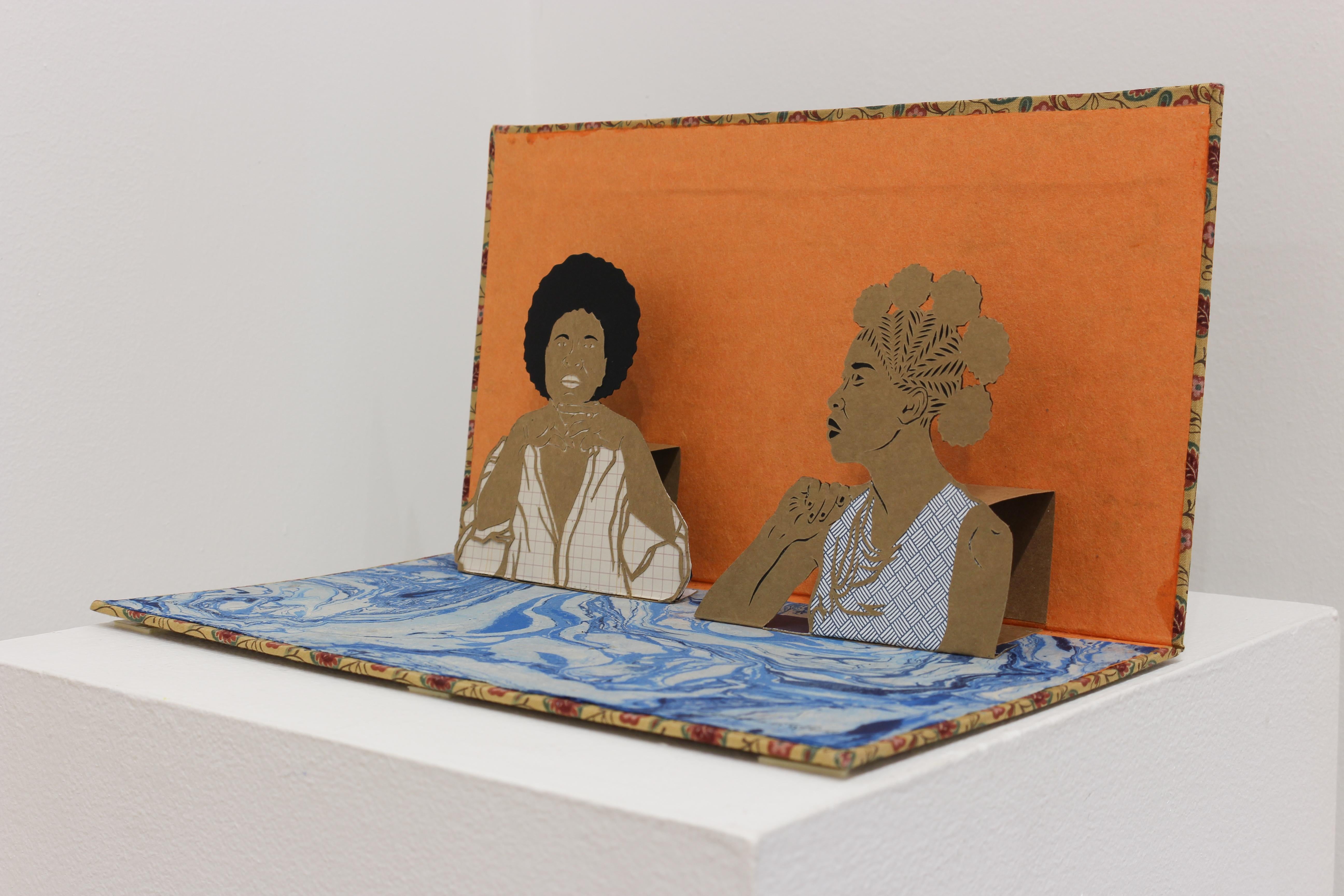 'In the Silences' is a simple pop-up book featuring two figures. Hues of blue, orange and brown. 

Jerushia Graham is inspired by the works of Elizabeth Catlett, Kerry James Marshall, John Biggers, Leo & Diane Dillon, Norman Rockwell and Kara