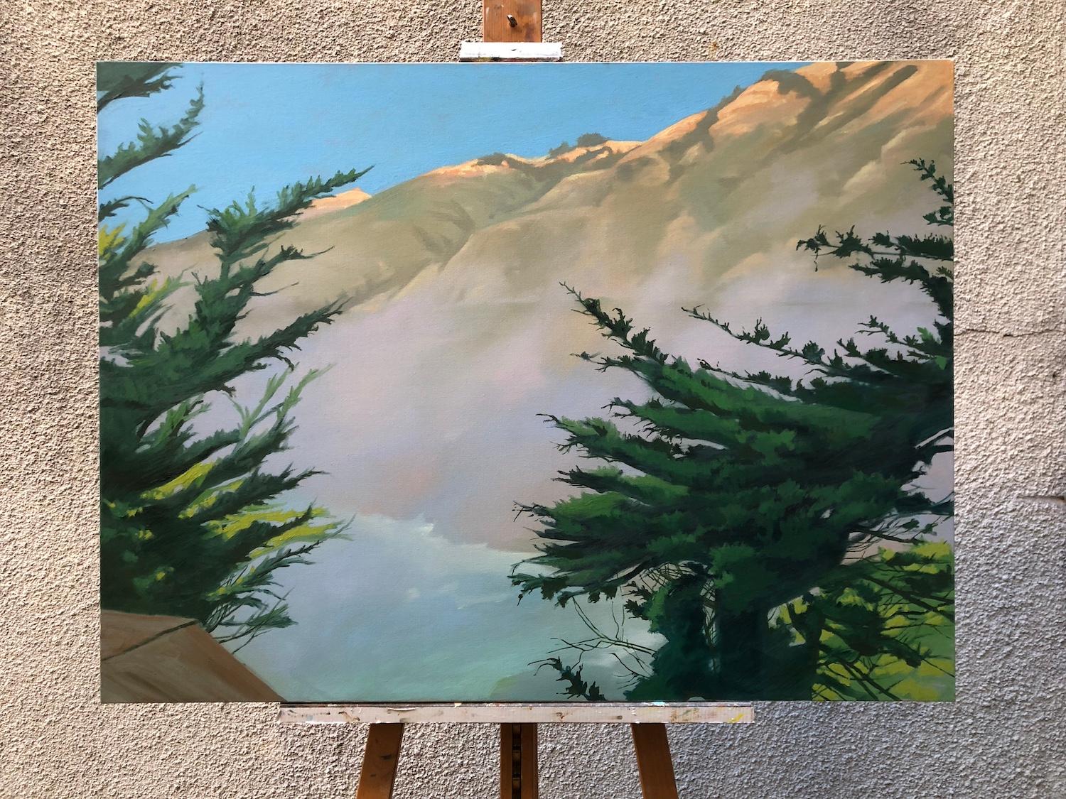 <p>Artist Comments<br />Fog rolls gently against the steep walls of Big Sur, softening the rugged cliffs. A faint line traces the path of Highway 1 as it winds north from Ragged Point. Sunlight bathes the landscape in a golden glow, while the trees
