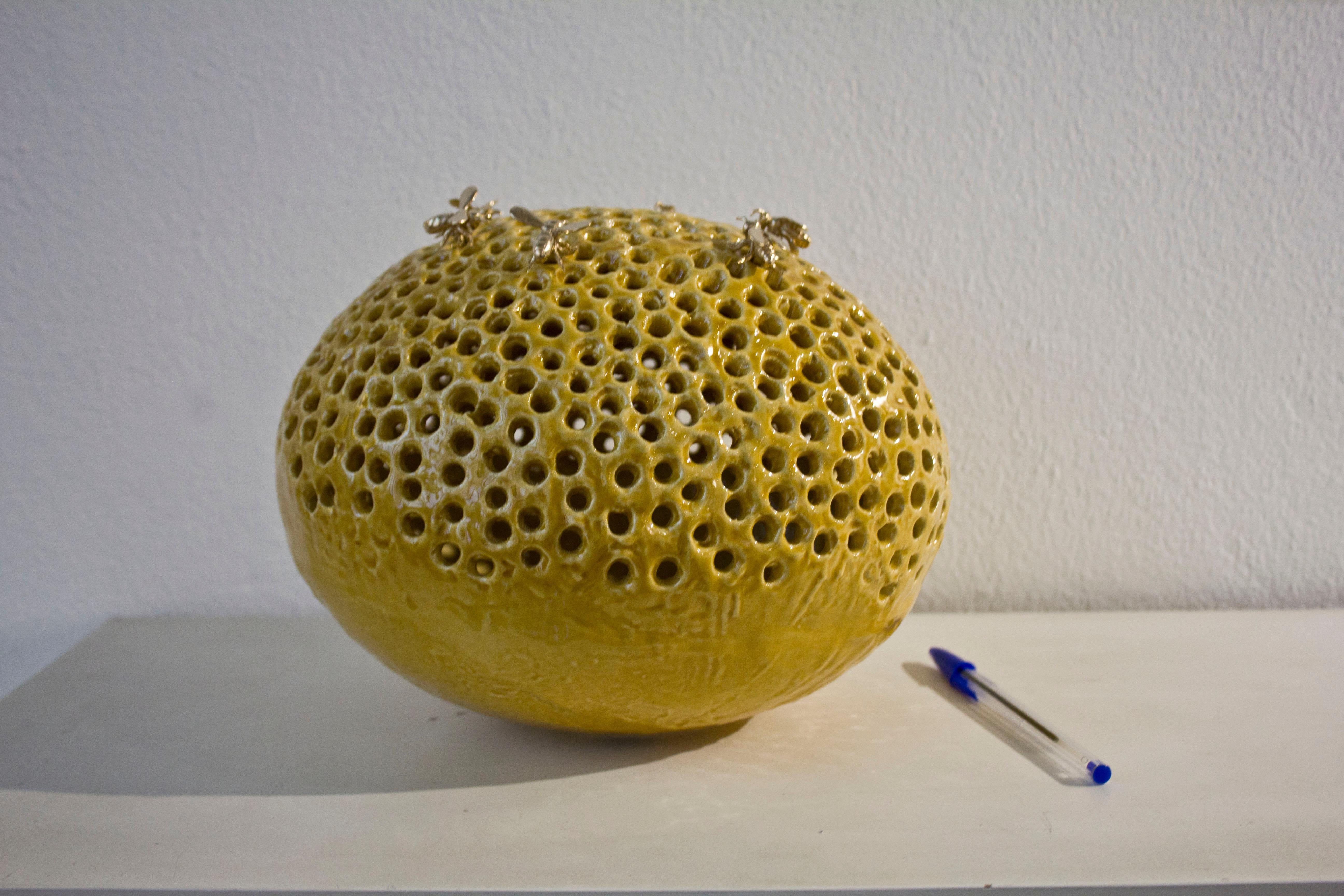 La sculpture ovale est réalisée en céramique avec une patine couleur miel difficile à produire. L'artiste a collaboré avec le meilleur four artistique d'Italie, Gatti. 

La sculpture est complétée par six abeilles en bronze amovibles. Une œuvre