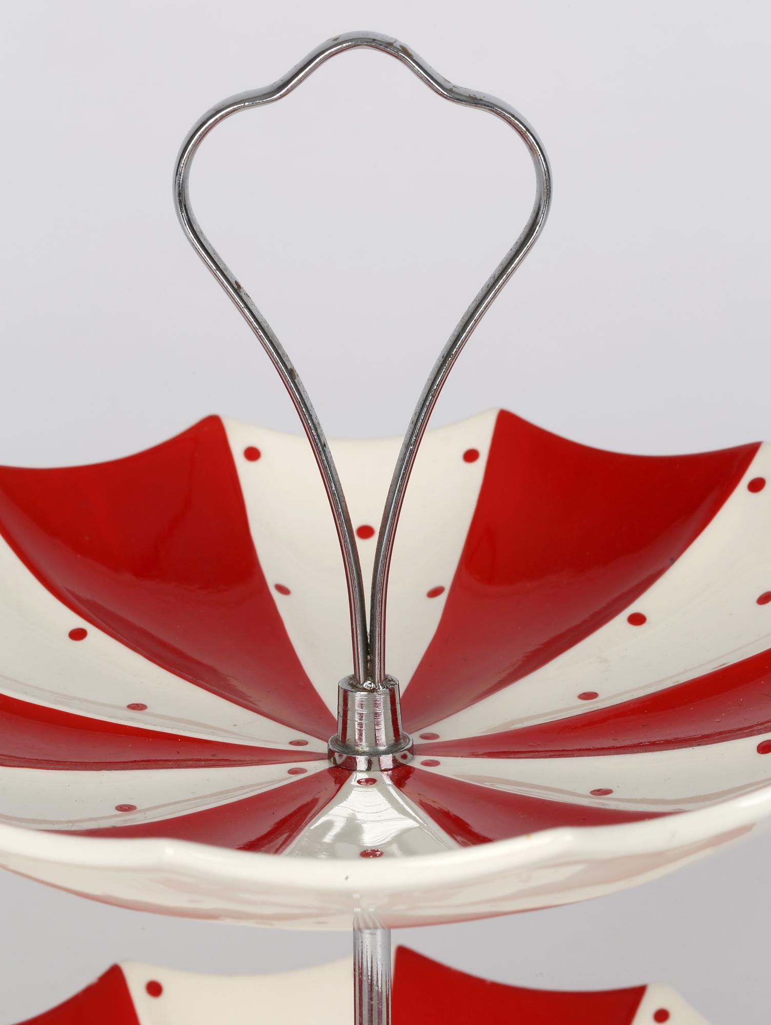 A very stylish mid-century Midwinter Modern Fashion Shape two tier cake stand in the red domino pattern and modelled as two umbrellas by prolific ceramic designer Jessie Tate (English, 1928-2010). The cake stand comprises of two umbrella shaped and