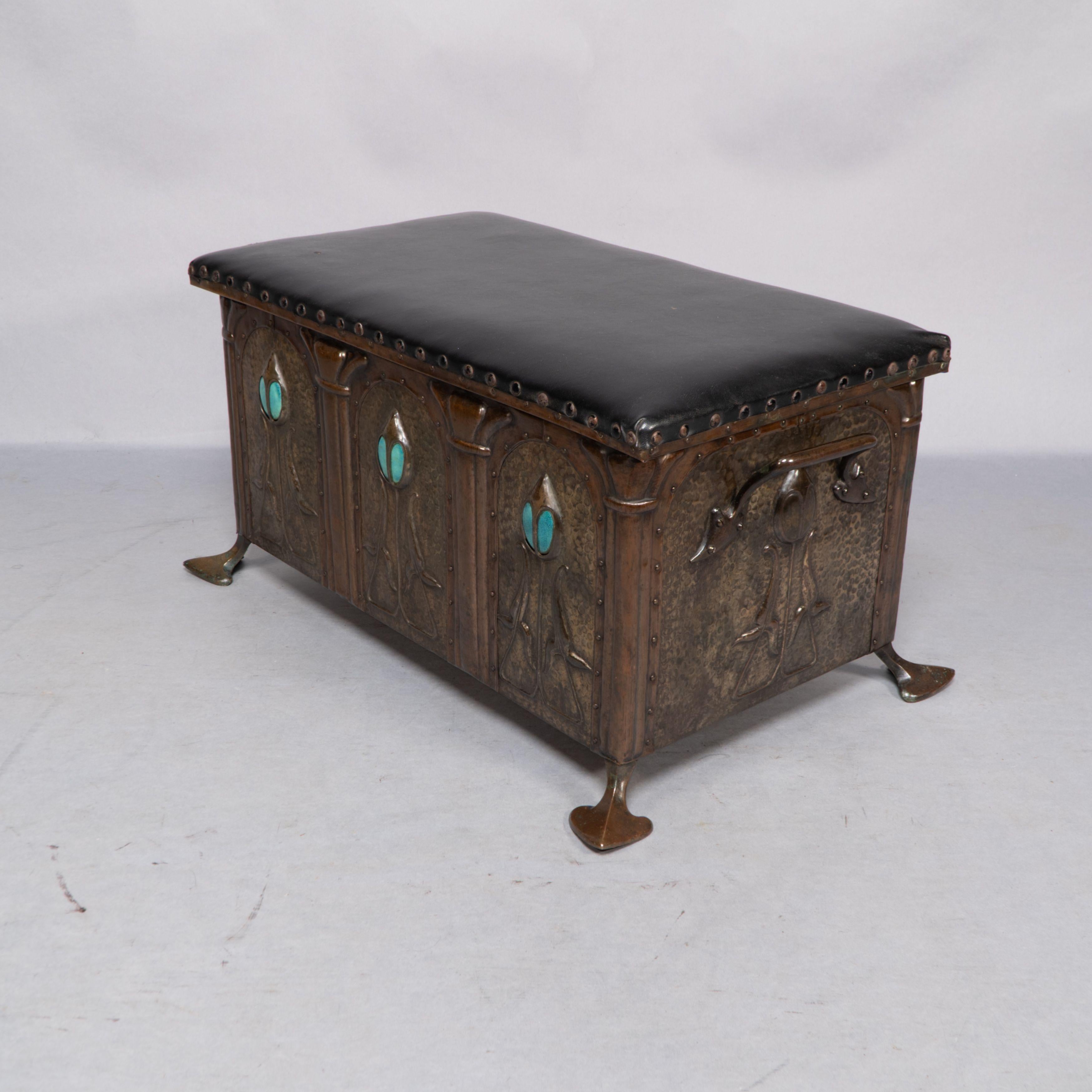 The front displays three hand worked flowers with electric blue Ruskin ceramic jewels inset behind the flower heads. Each flower panel is riveted into arched frames and separated by faux columns. The sides have bronze cast organic handles and the