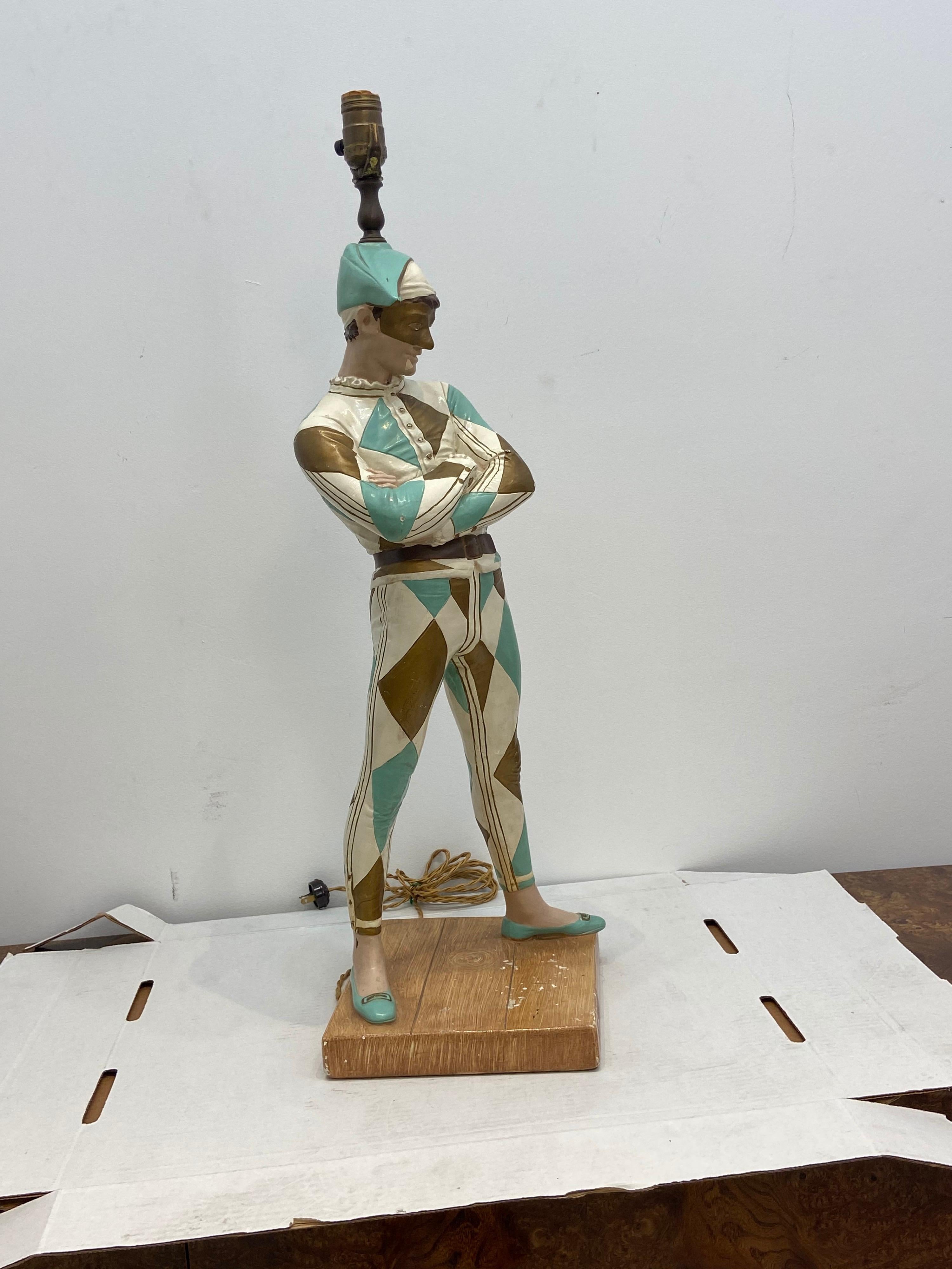 A large harlequin /jester style lamp in vibrant blues whites and gold on a faux wooden base possibly Marbro.