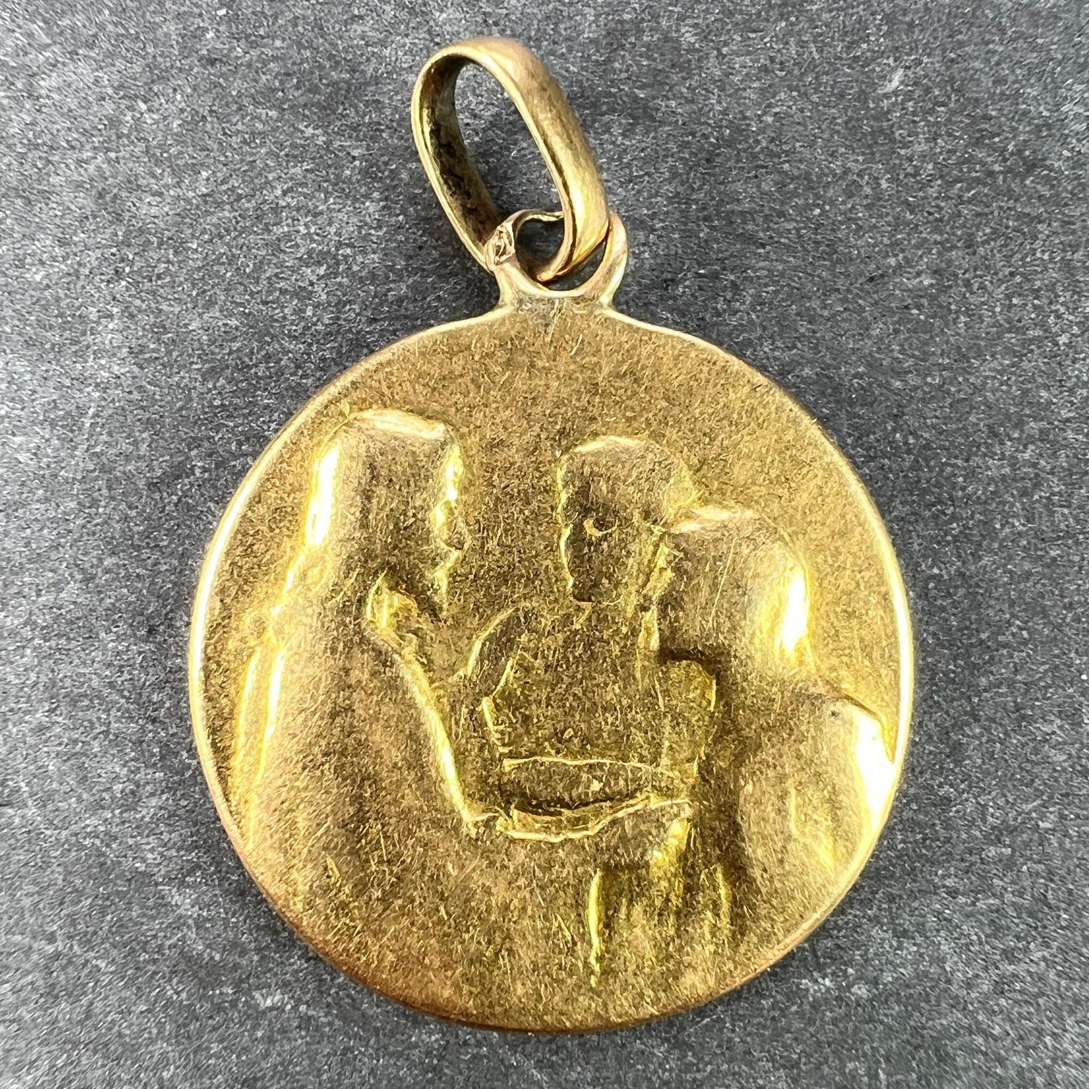 A French 18 karat (18K) yellow gold charm wedding pendant designed as a medal depicting Jesus Christ blessing the marriage of a man and woman. The reverse depicts a sheaf of roses and lilies, engraved with the initials PM MG and the date 20 Mai