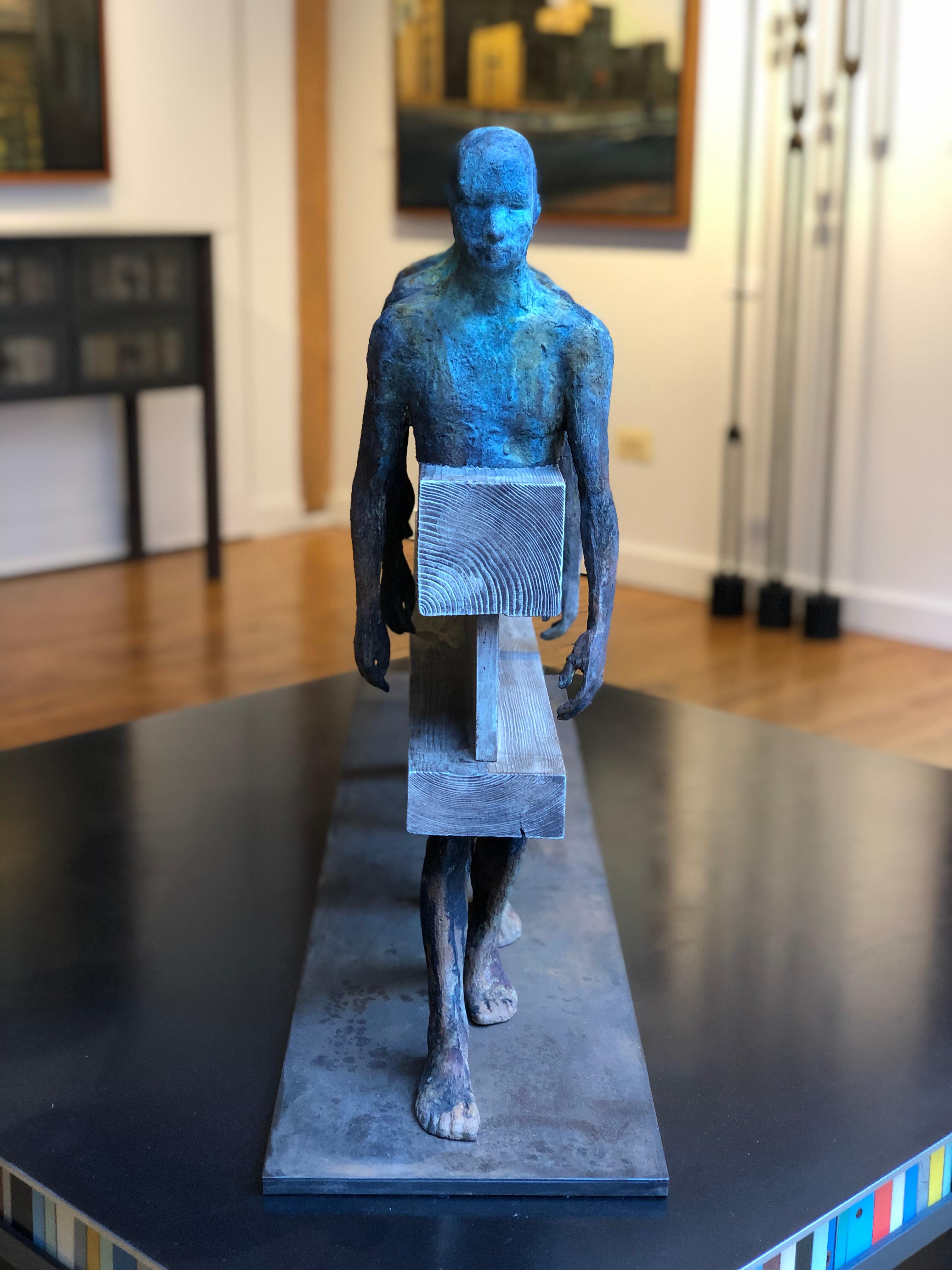 Three figures walk in tandem in this bronze, steel and wood sculpture.  Their bodies are connected and abstracted by a steel and wood beam.  The figures are patinead in green verdigris and brown rust.  The wood and steel beam is finished in a