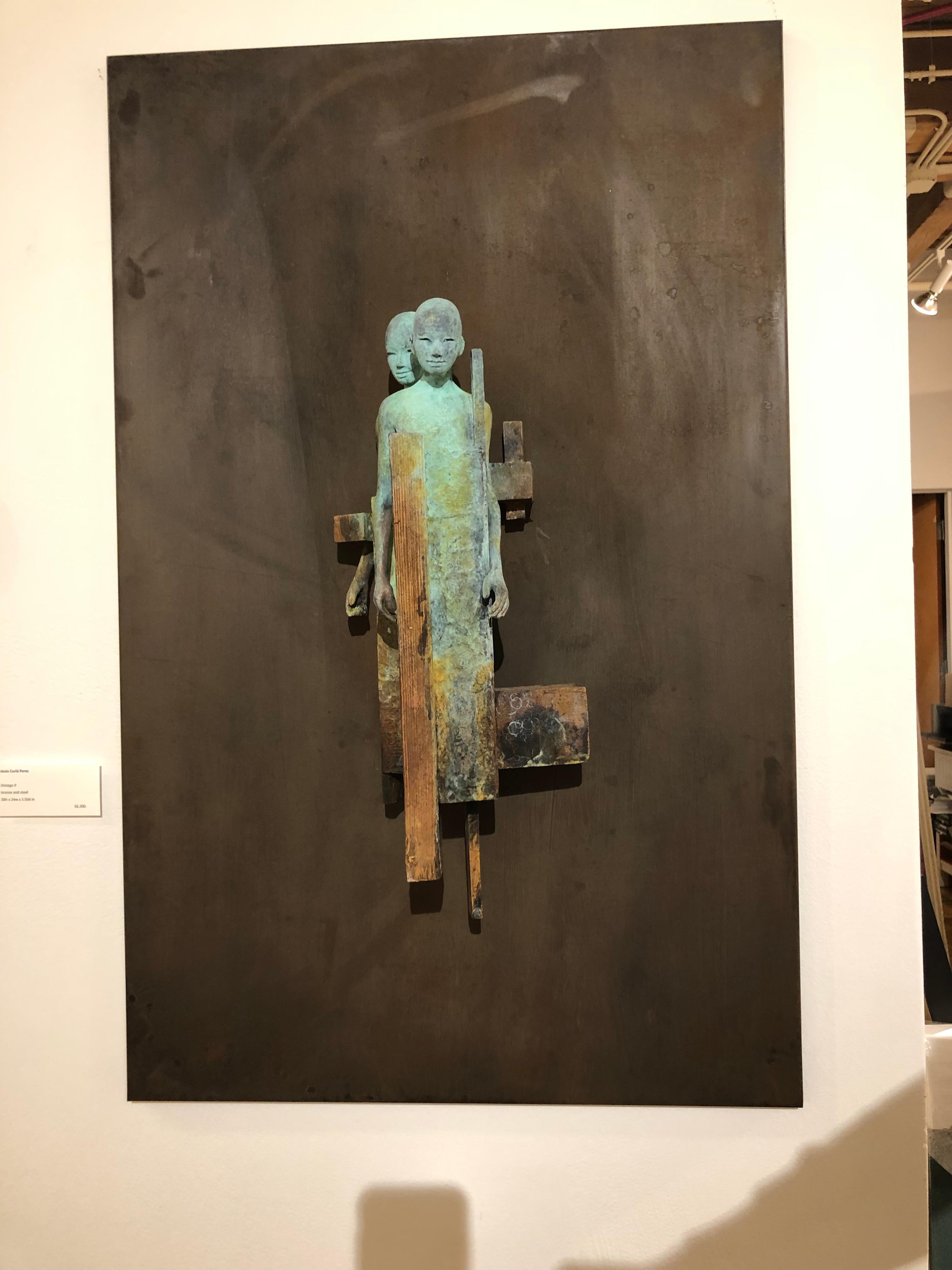 This bronze and steel wall sculpture contains two abstracted figures whose bodies are intertwined and bound together inside a cocoon of geometric and organic shapes.  The combination of matte rust and verdigris bronze emphasize the depth of the