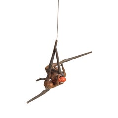 Lucha I - Escultura colgante de figuras de bronce entrelazadas con capucha naranja