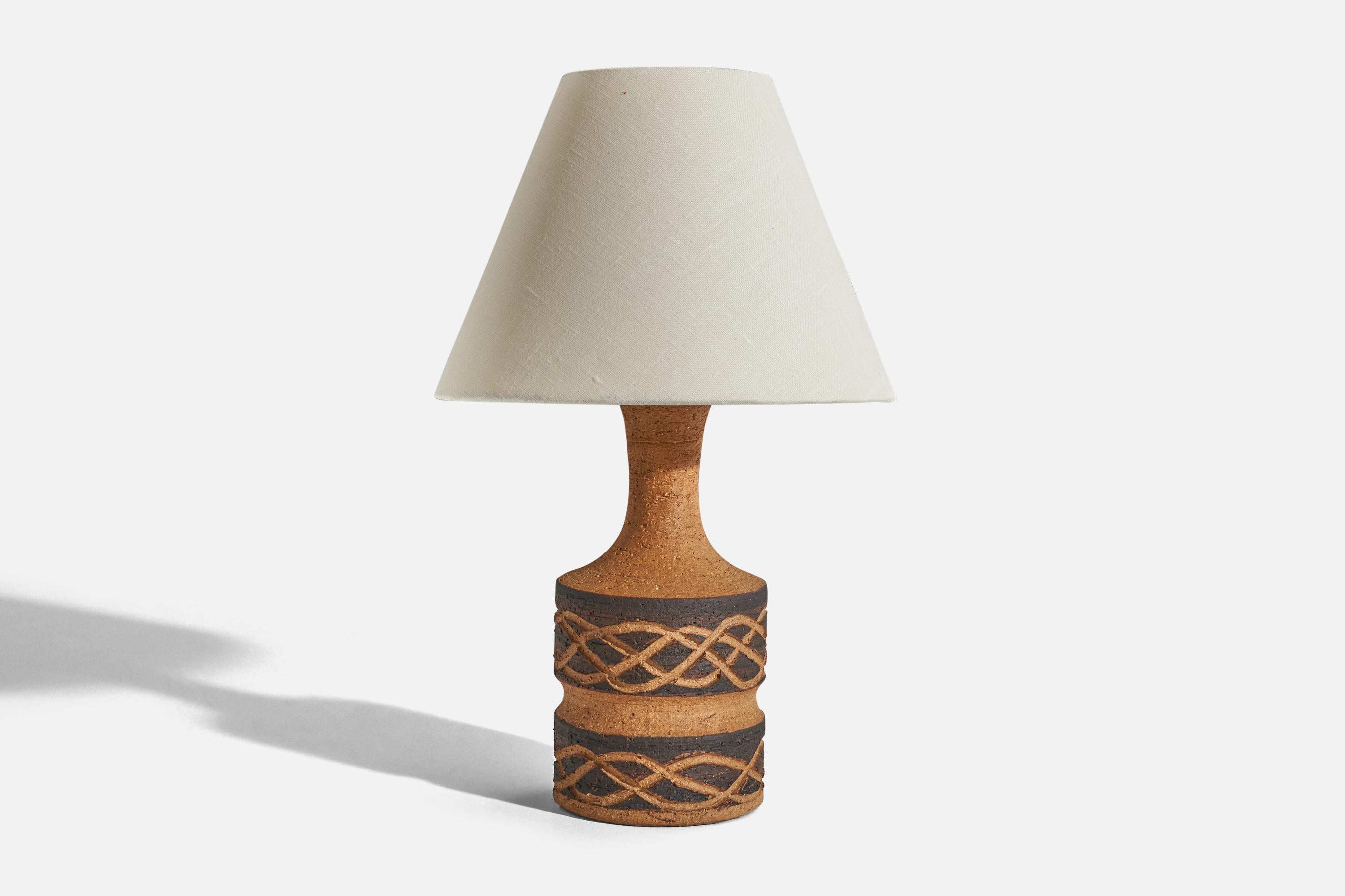 A black and brown, glazed stoneware table lamp designed and produced by Jette Hellerøe, Denmark, 1960s.

Sold without lampshade. 
Dimensions of lamp (inches) : 10.12 x 4 x 4 (H x W x D)
Dimensions of shade (inches) : 4 x 8.25 x 6.25 (T x B x
