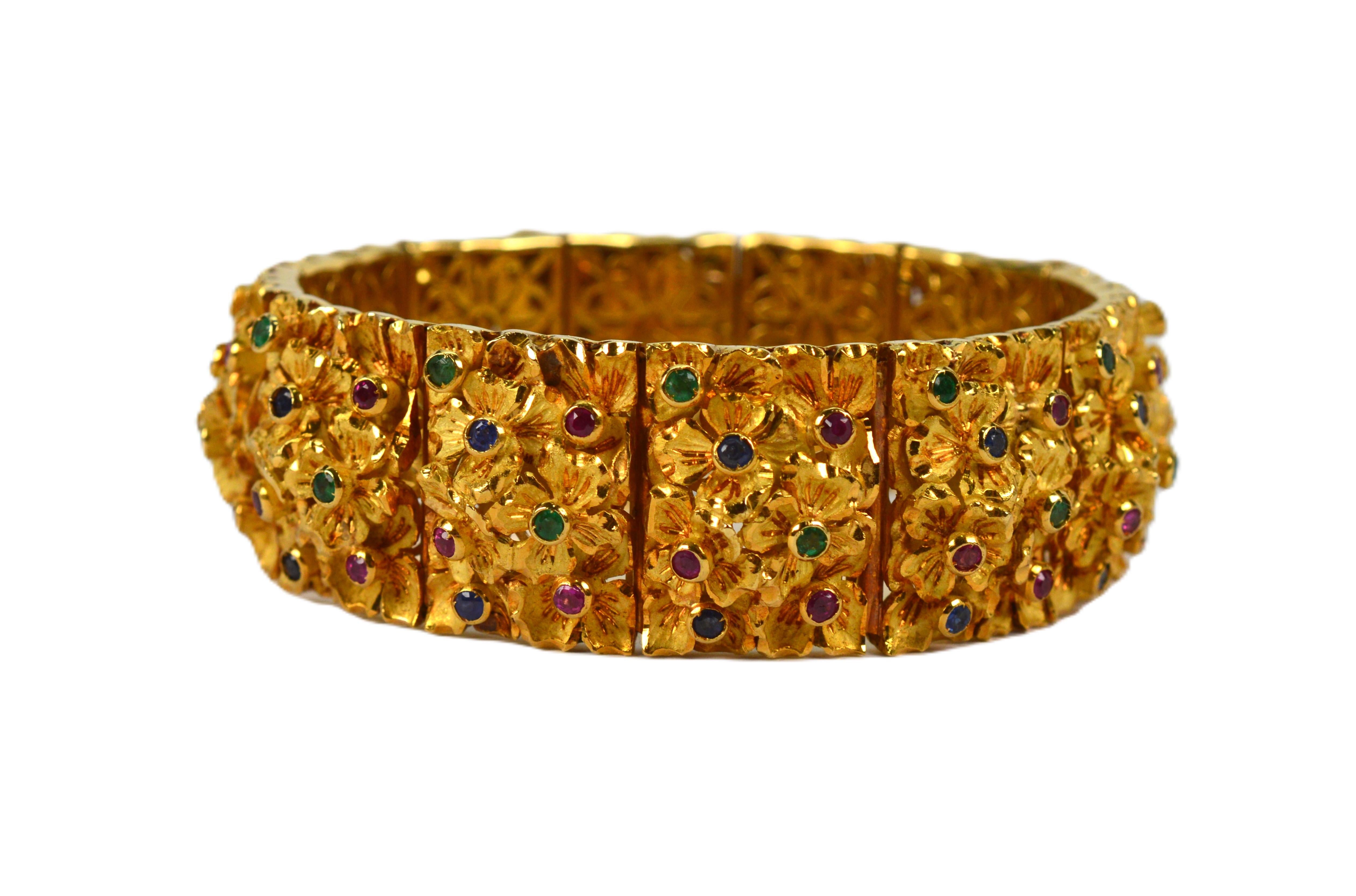 Sculptured in rich 18 karat yellow gold, this custom luxury bracelet displays a unique floral inspired design which incorporates petals of satin gold artfully accented with brightly polished gold enhancements which elevate the details and the