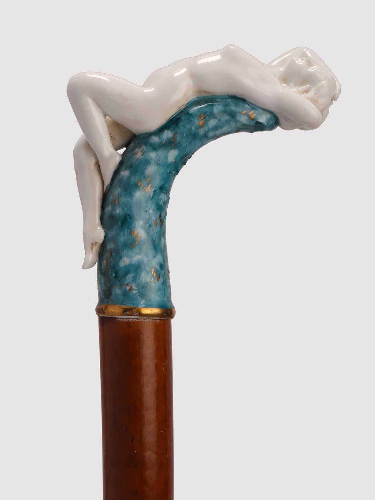Walking stick with porcelain knob, light spotted rattan wood shaft, iron and brass ferrule. The knob has a curved profile, it is made of porcelain. It rises from the stem with a ring, and has a curvilinear profile, underlined in gold. The handle is