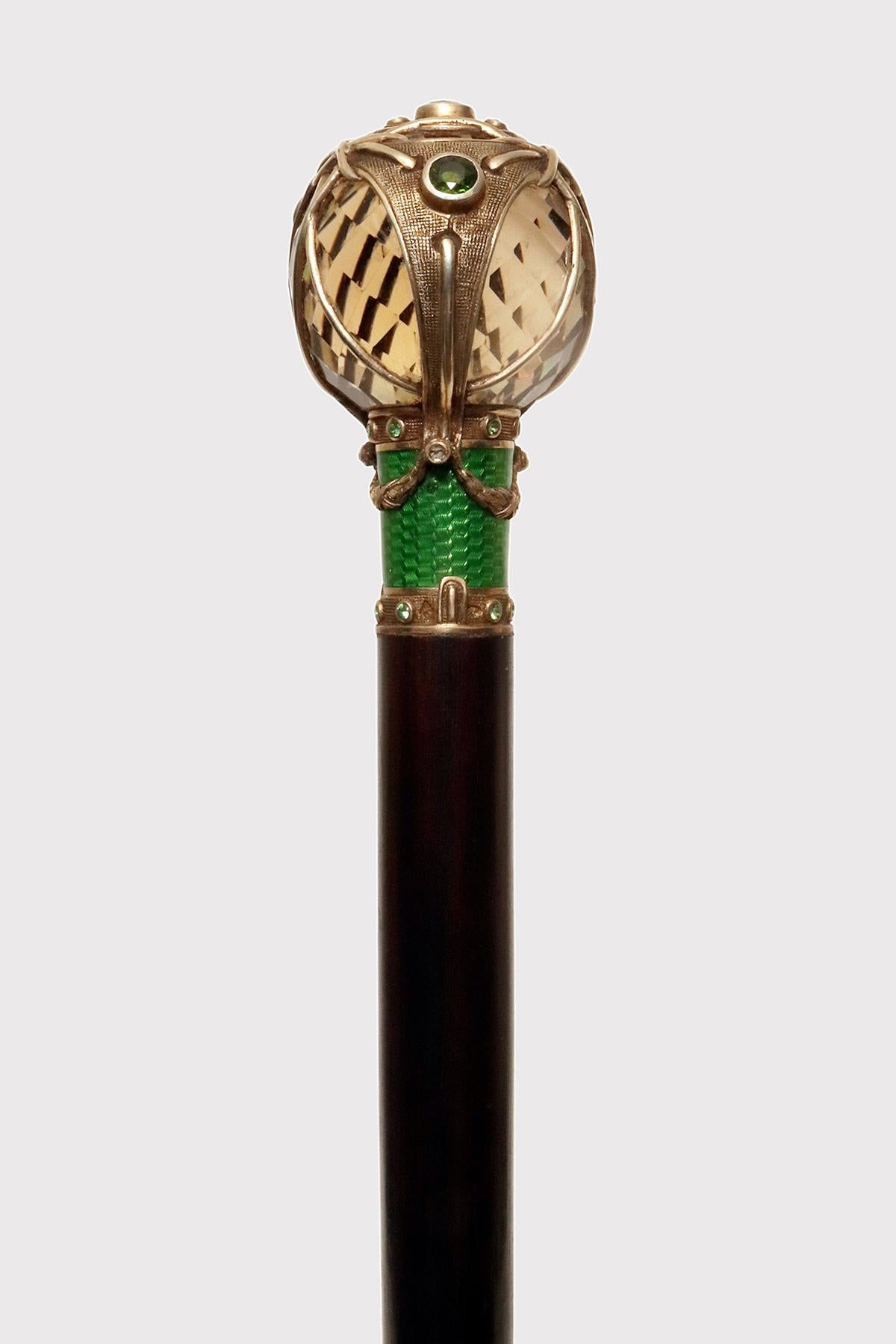 Georges Fouquet walking stick, Paris, circa 1900, signed. Knob with faceted smoky quartz sphere inside an open 18K gold cage. Ribbons with 4 faceted cut green tourmalines, 18K gold band and green guilloche enamel. Ebony wood barrel. Alphonse