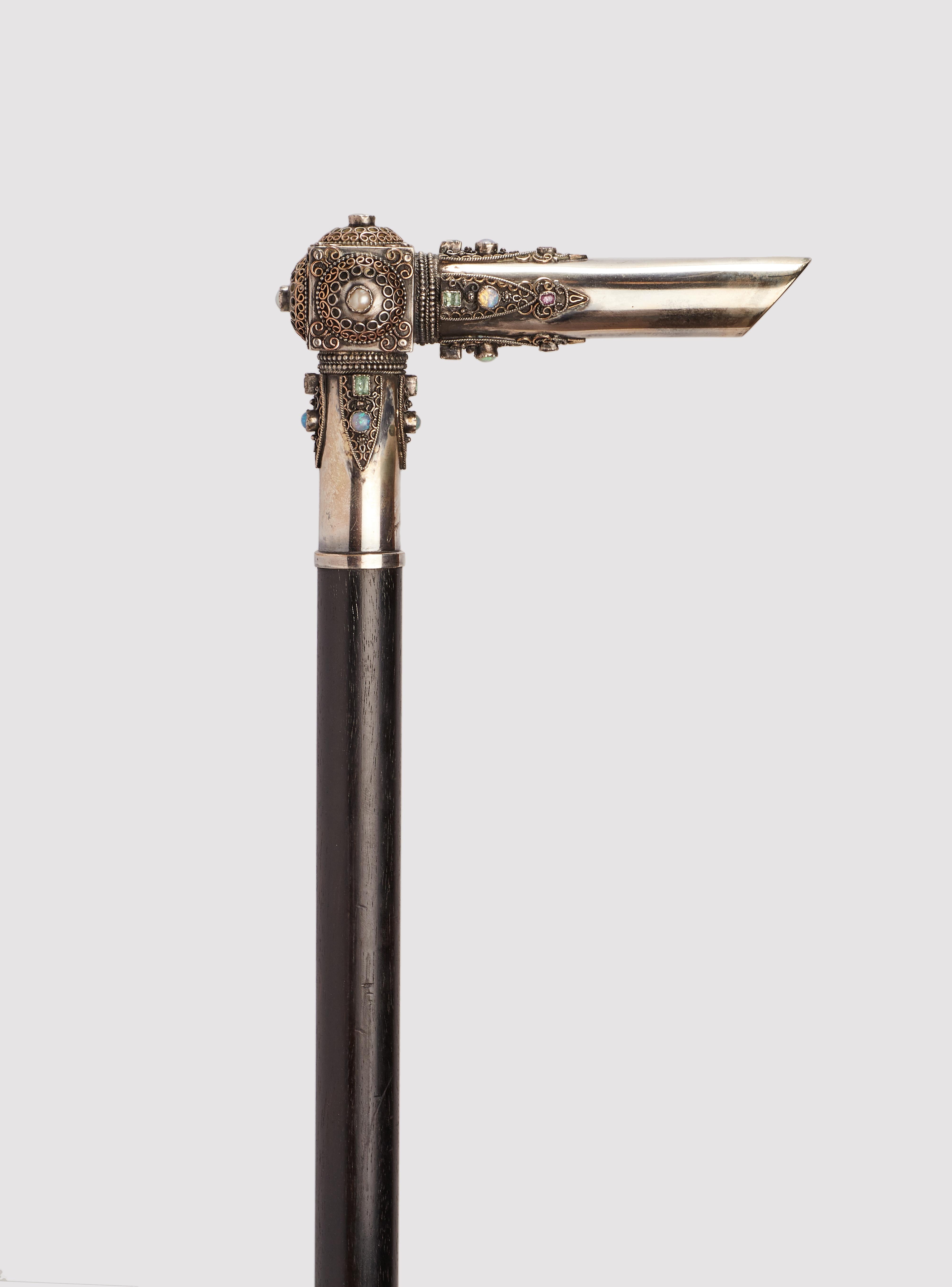 Walking stick: jewel  cane L shape handle made out of silver with 18K gold filigree and precious stones: pearls, opals, rubis, tourmalines. Ebony wood shaft. Metal ferrule. Sophie Sander-Noske, France 1900-1910.