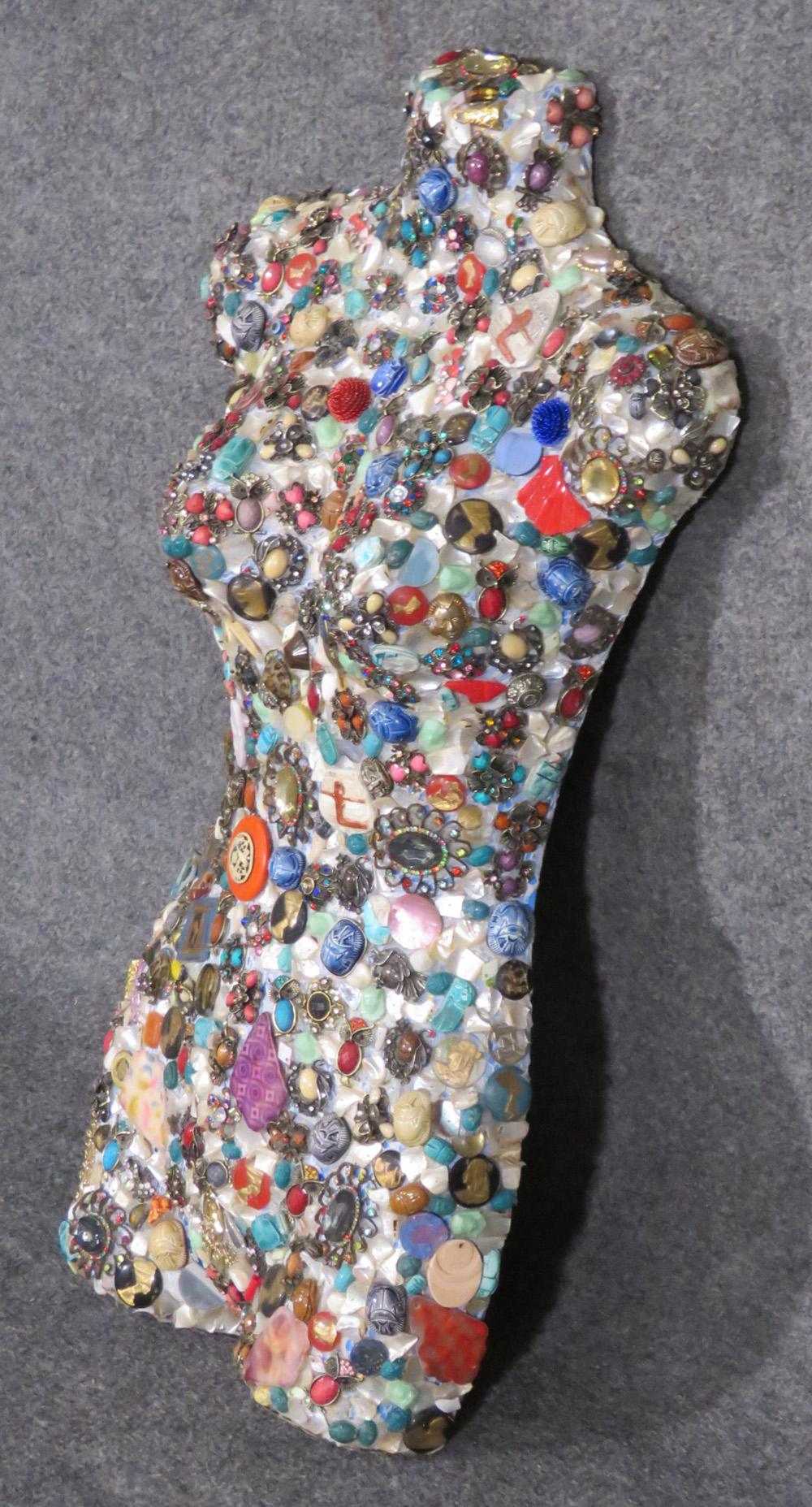 Measures: 29 tall x 16.5 wide x 5.5 deep

This is a gorgeous jeweled torso or mannequin. The body is studded with jewels, scarab beetles and various other beautiful objects. This is an artist's piece. Dates to the 1960s and is an interesting item