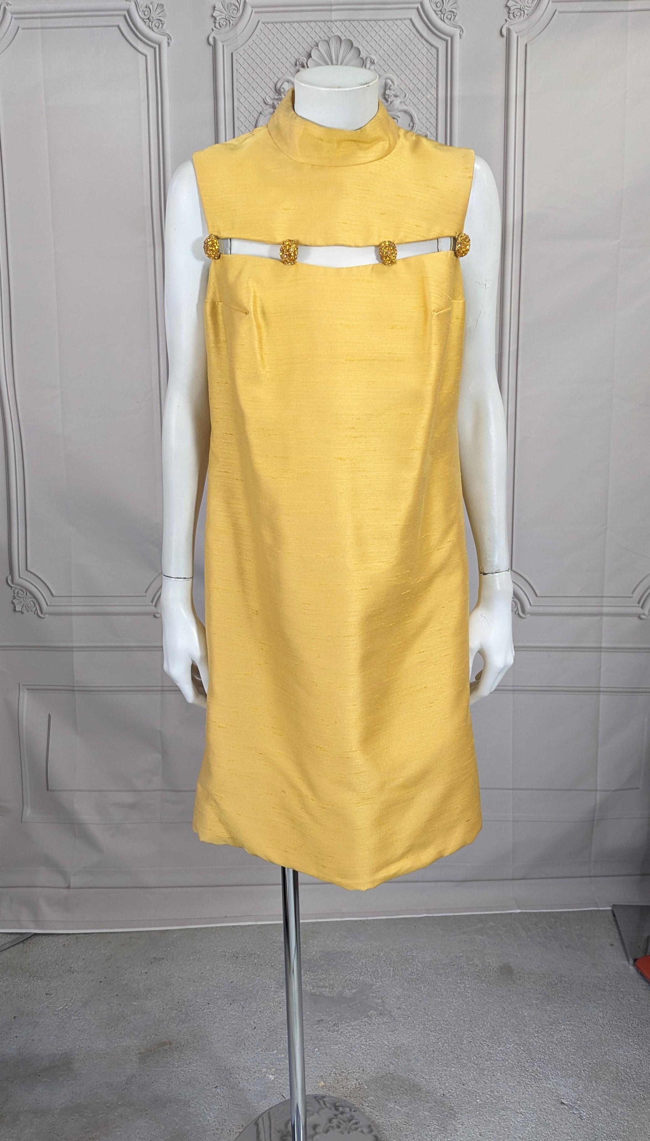 Jeweled Raw Silk Gold Mini Dress from the 1960's. Cut with a opening above bust which is held with citrine paste decorated buttons. Cool design with shaped neckline. 1960's USA. Fully Lined. Hook and zip entry. 