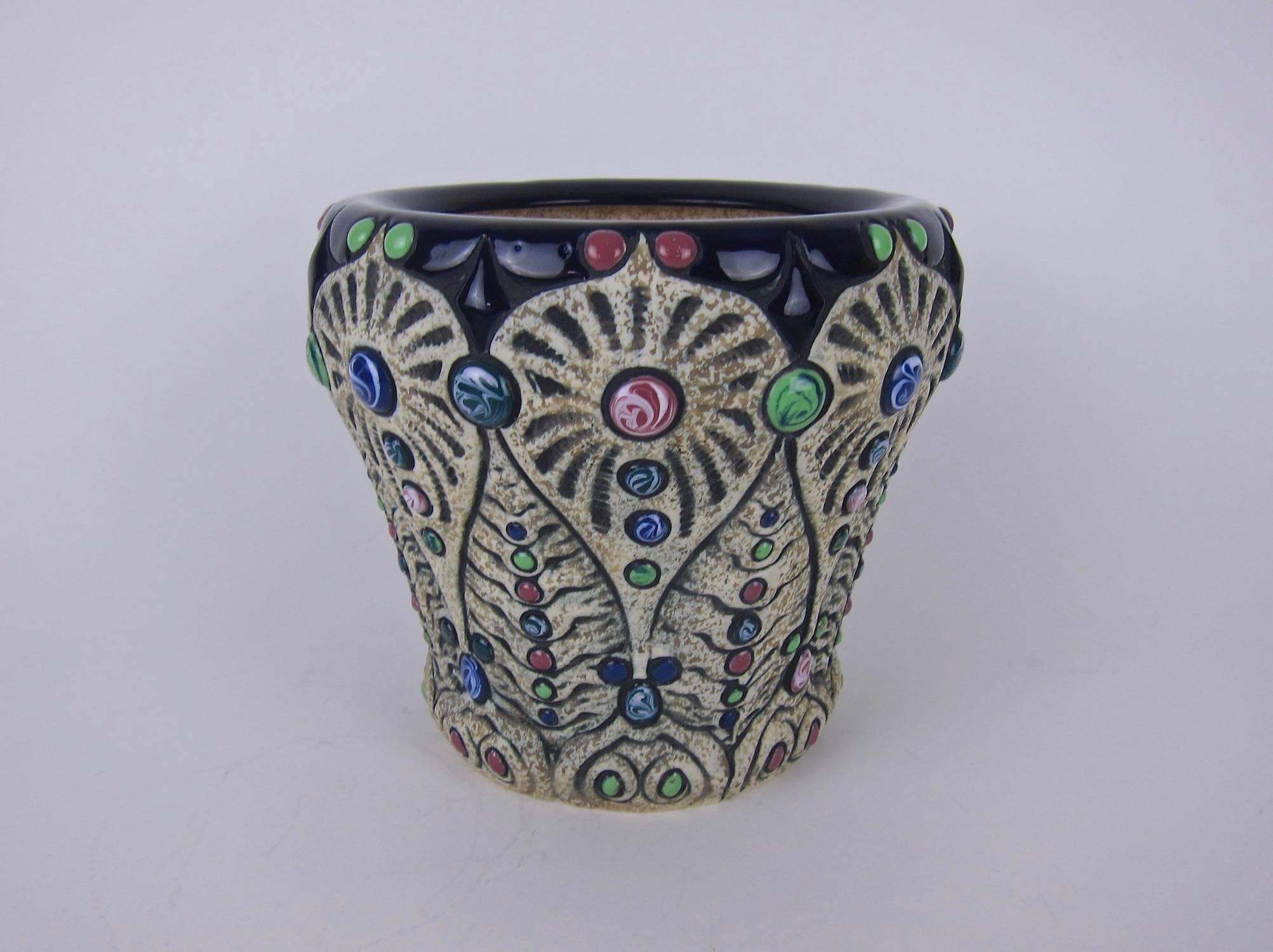 A vintage Amphora pottery jeweled cachepot or jardinière—that can easily be a large vase—made between 1918 and 1939. The Art Nouveau vessel has a wide rim glazed in glossy dark blue above a matte body featuring stylized, hand-carved decoration