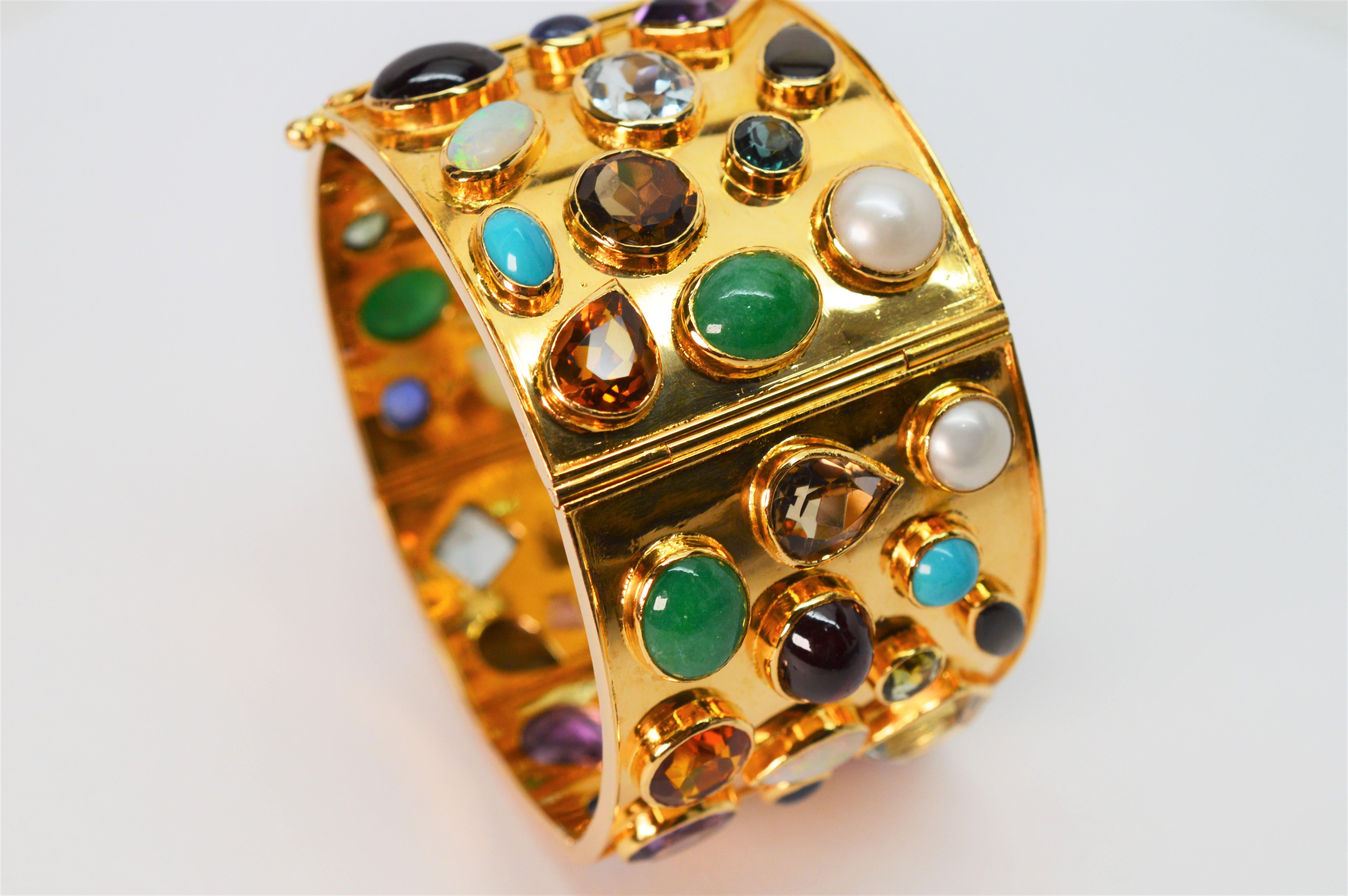 Place yourself in the spotlight with a rainbow of color and brilliant shine from this thrilling jeweled wide cuff bracelet in eighteen karat 18K yellow gold. This spectacular piece is artisan made with an eclectic and colorful mix of natural