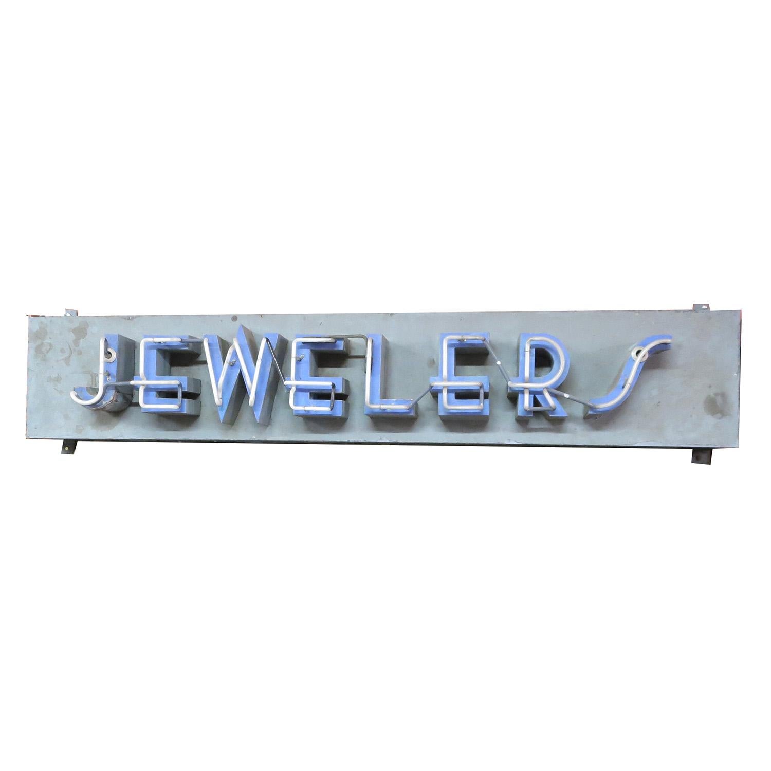 This great old sign once hung over the doorway of a jewelry store in the 1930s. The raised metal lettering is super stylized, and trimmed in blue neon. The painted metal can is original, and shows a charmed fading to the paint. The sign is self
