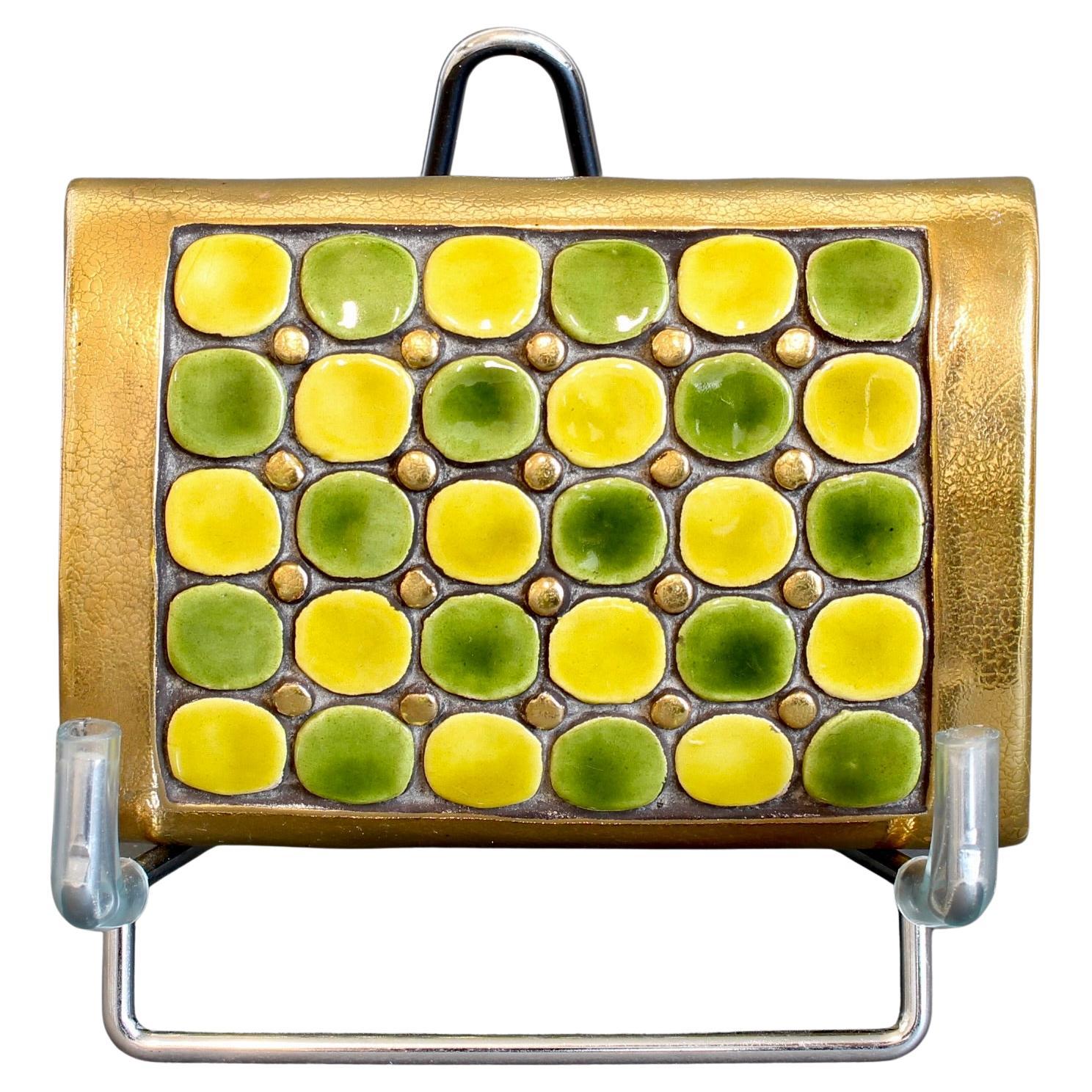 Jewellery box with decorative ceramic lid by Mithé Espelt (circa 1960s). A series of yellow and green imperfect circles appear on the cover of the box like stepping stones in a garden. Interspersed amongst them are smaller golden studs adding