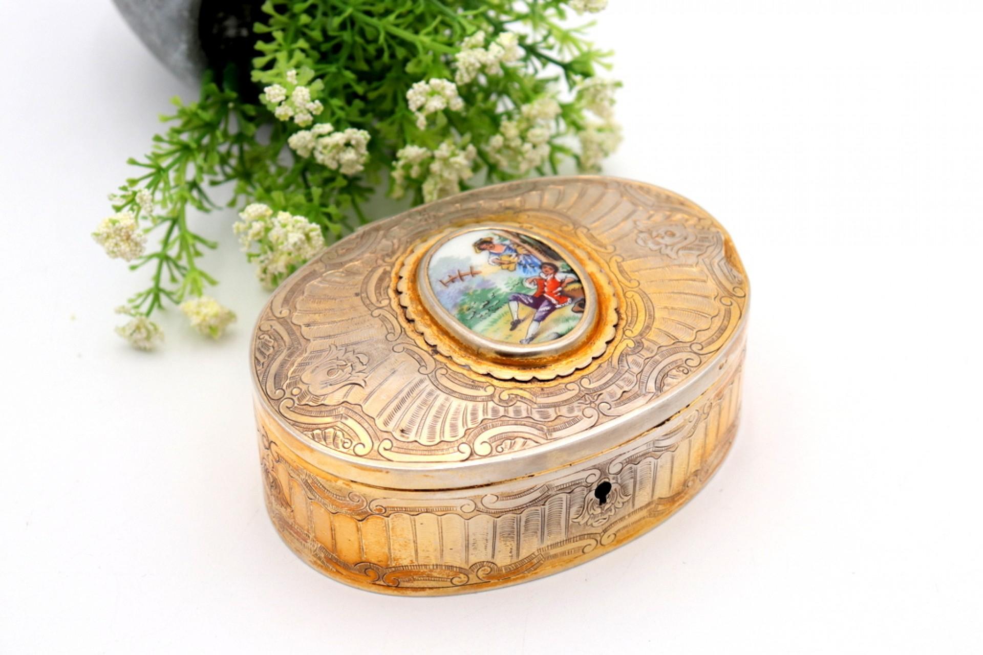 Description: Silver jewelry box with reliefs and an idyllic scene on enamel and velvet inside. Metal: Silver. Origin: Portuguese. Mark: standing eagle. Weight: 260.41 grams. Dimensions: 13cmx9cm. Content: 833/1000. Assay Mark: Yes, between 1938 and