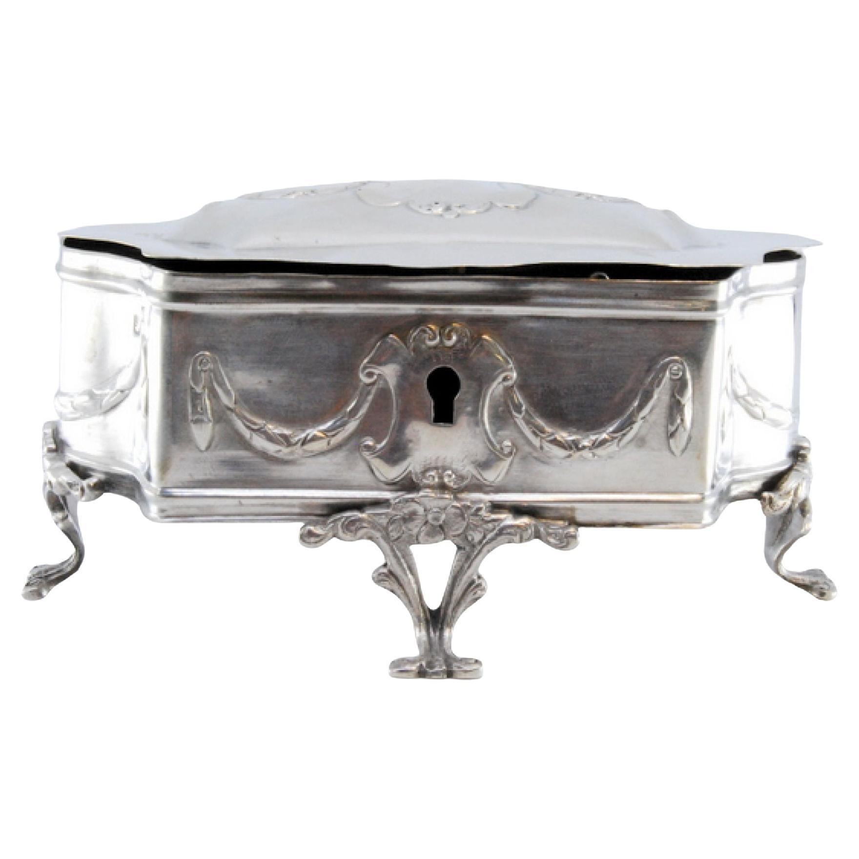 Jewelry box, silver embossed with bows and resting on four cut-out feet