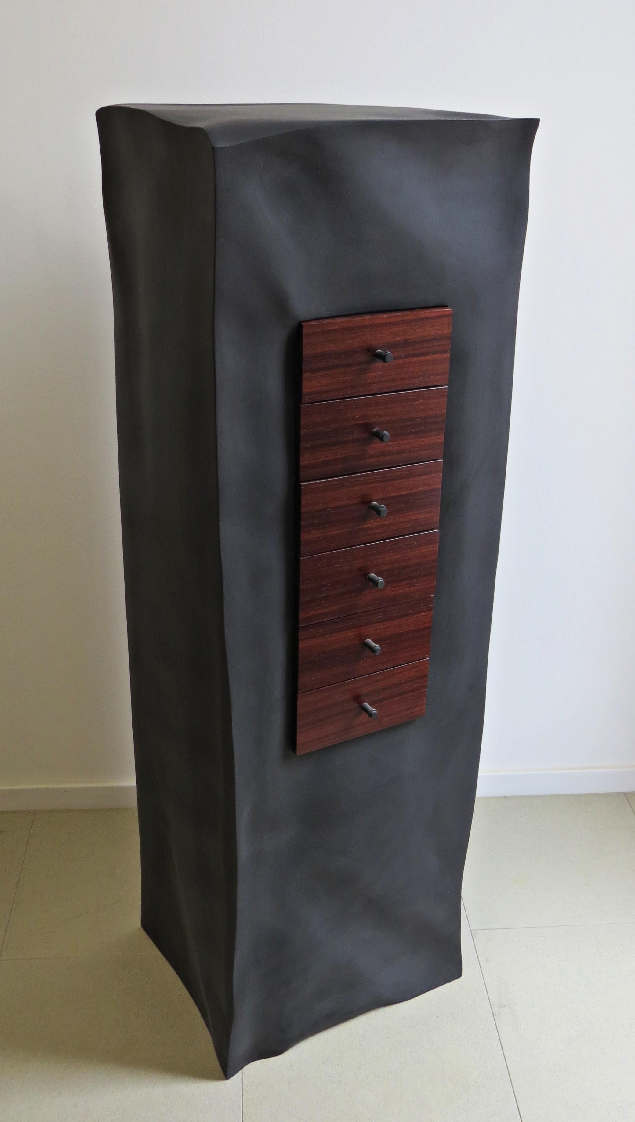 A black body made of plywood, which is organically elaborated with wrinkles and wrinkles sculptural, form the housing.
This is coated with deep matte panelling.
The six mahogany drawers are integrated.