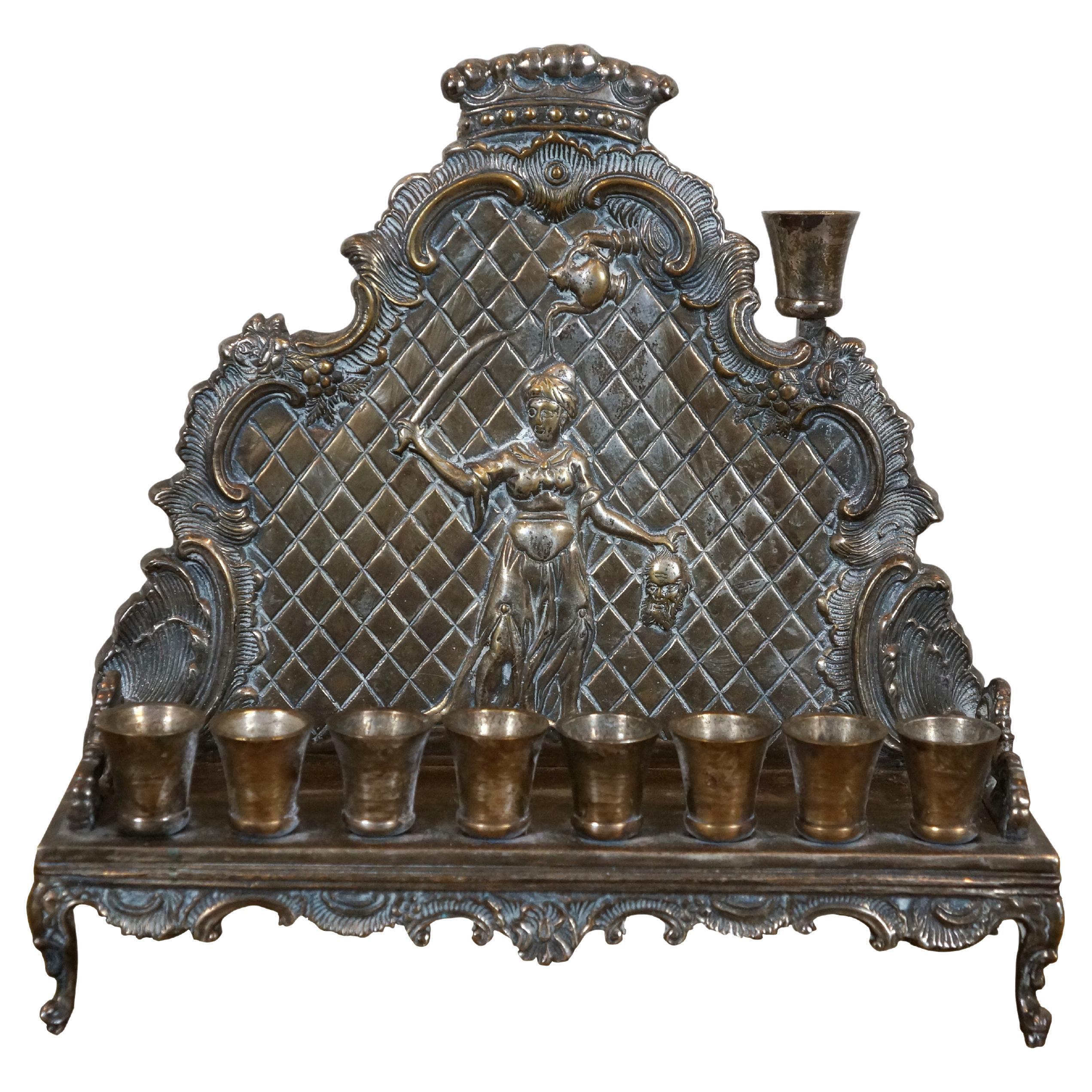 Large, heavy, vintage, late 20th-century silver-plated menorah, produced by The Jewish Museum. Design features eight screw-in candle cups on a rectangular base with scalloped / foliate legs and edging, behind which is a backsplash depicting Jewish /