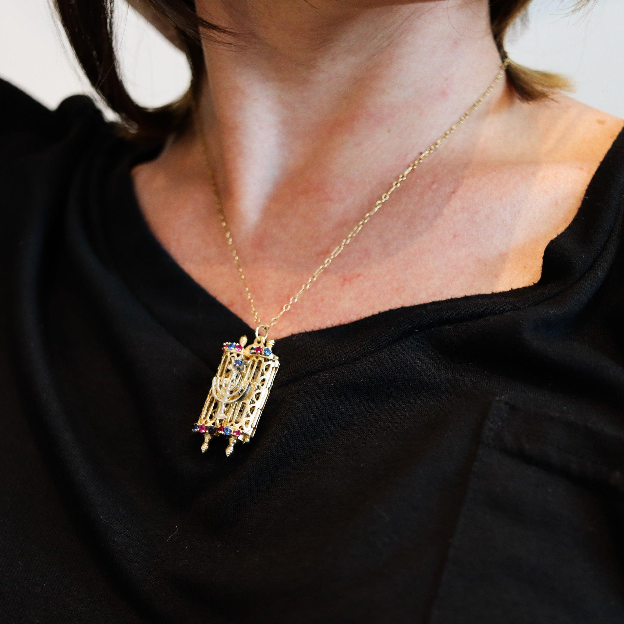 A Jewish Torah with Menorah pendant.

A nice modern pendant crafted in the shape of a Jewish Torah in solid yellow gold of 18 karats and accented with a Menorah in white gold. The pendant is embellished with thirteen lab-created gemstones associated