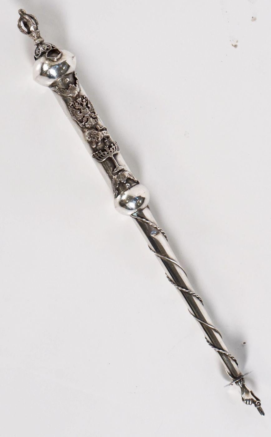 A fine Jewish yad or torah pointer of silver featuring a crown on the handle end, with a traditional pointed finger hand on the other end. With decorative symbols including a menorah and lion on the handle. A handsome find for the Judaica