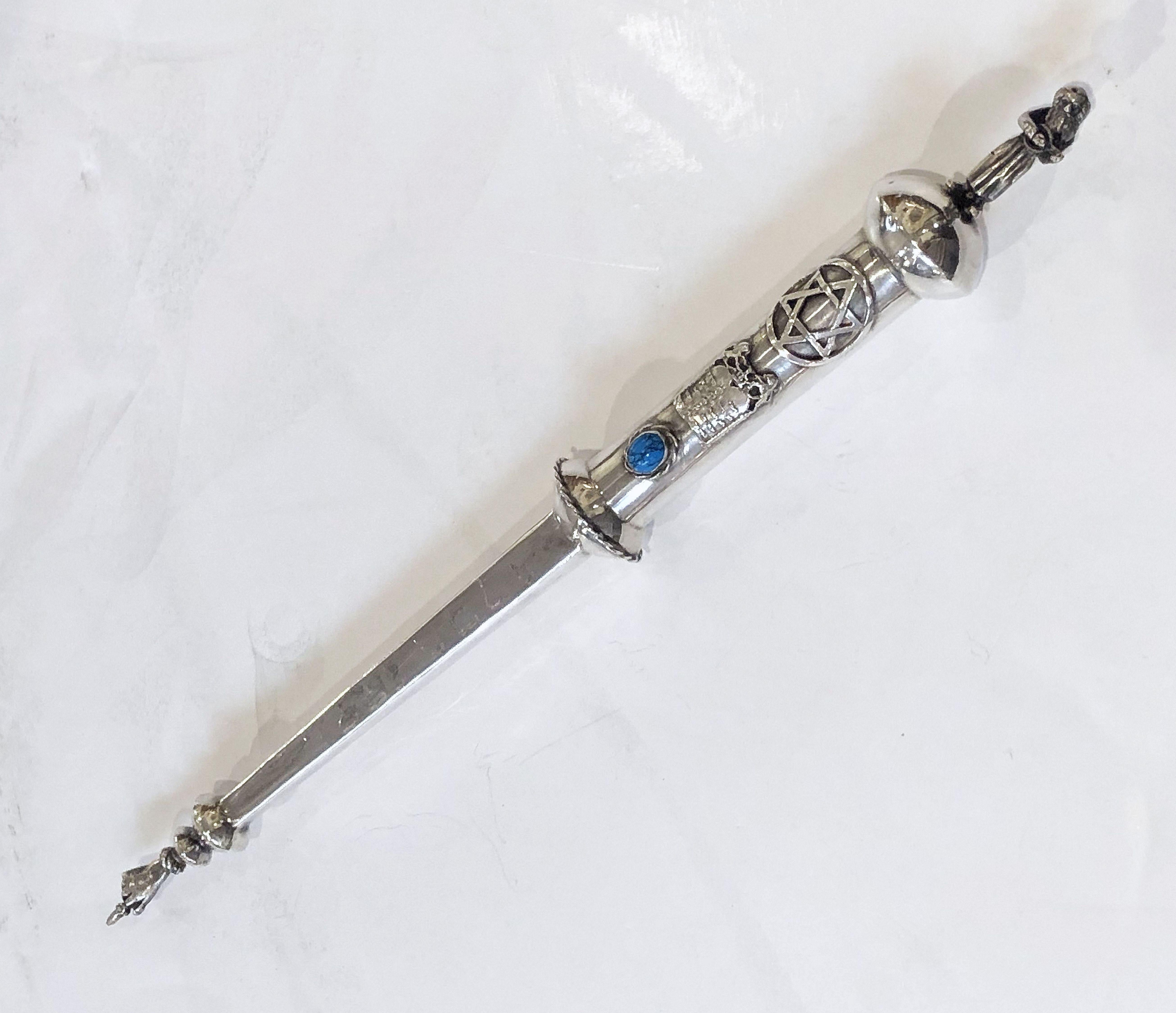 A fine Jewish yad or torah pointer of silver featuring a robed man playing a lute or similar stringed instrument on the handle end, with a traditional pointed finger hand on the other end. With decorative blue stone. A handsome find for the Judaica