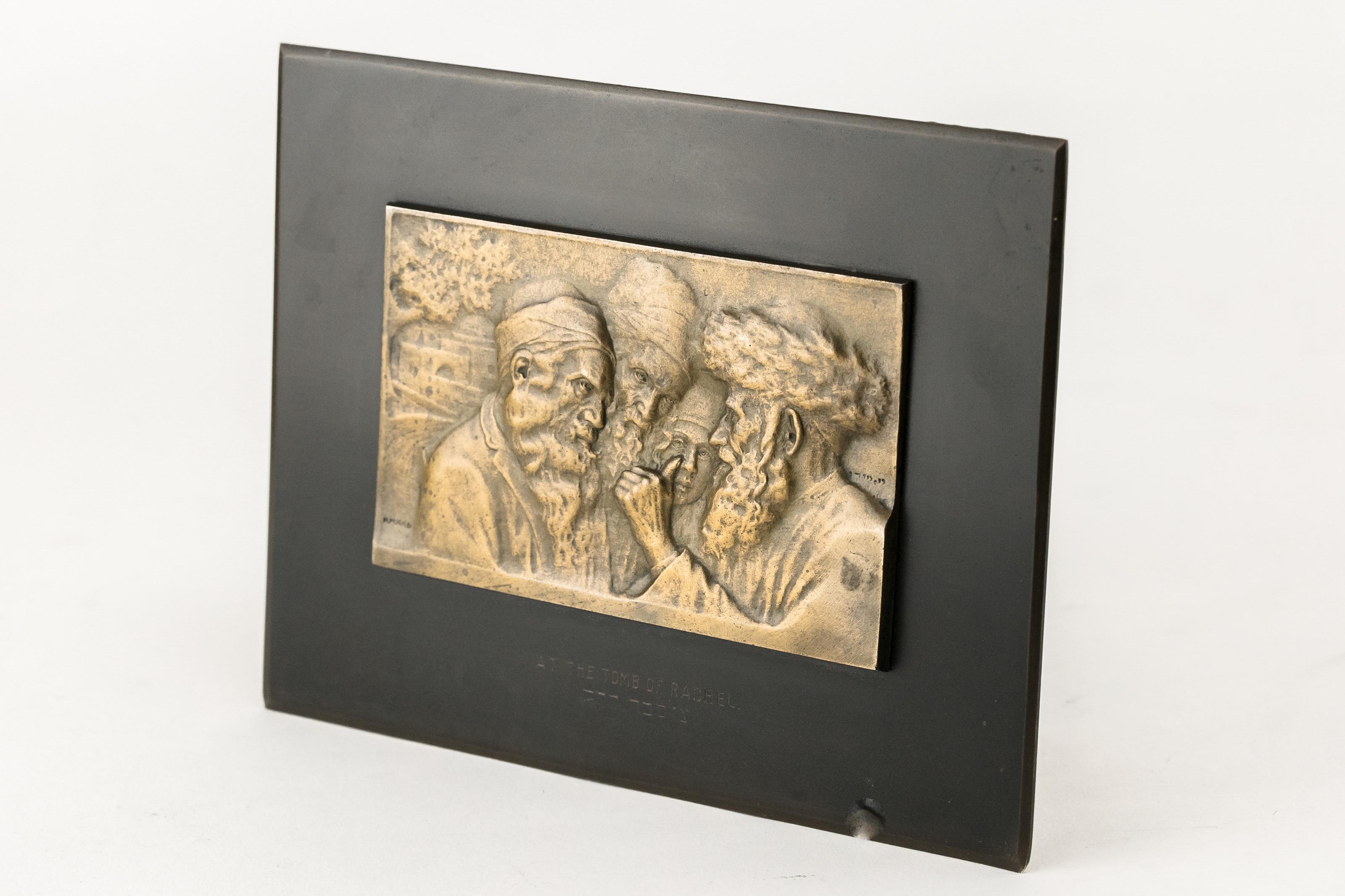 Bronze plaque with a relife of the figures of three elderly Jews and young Jew with Rachel's Tomb in the background. 
Made in Bezalel school, Jerusalem by Moshe Murro, circa 1915.
Signed: Bezalel